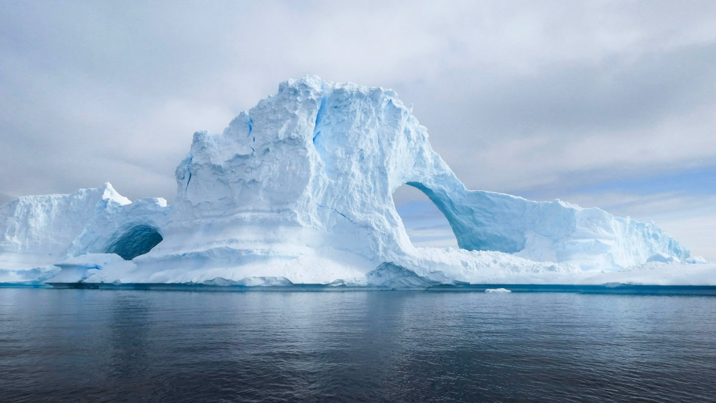 A huge arched iceberg floating in calm water off Antarctica
