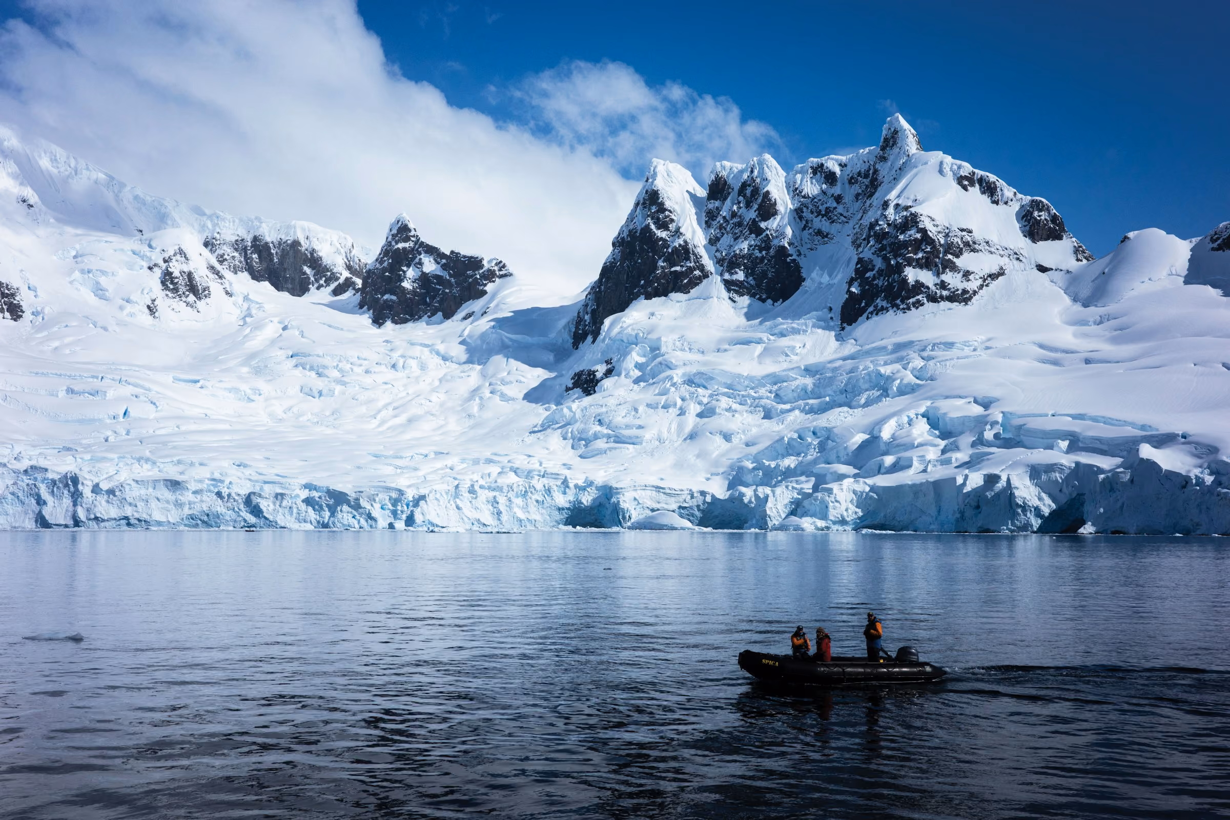 A Zodiac below snowy peaks and glaciers in an Antarctic bay
