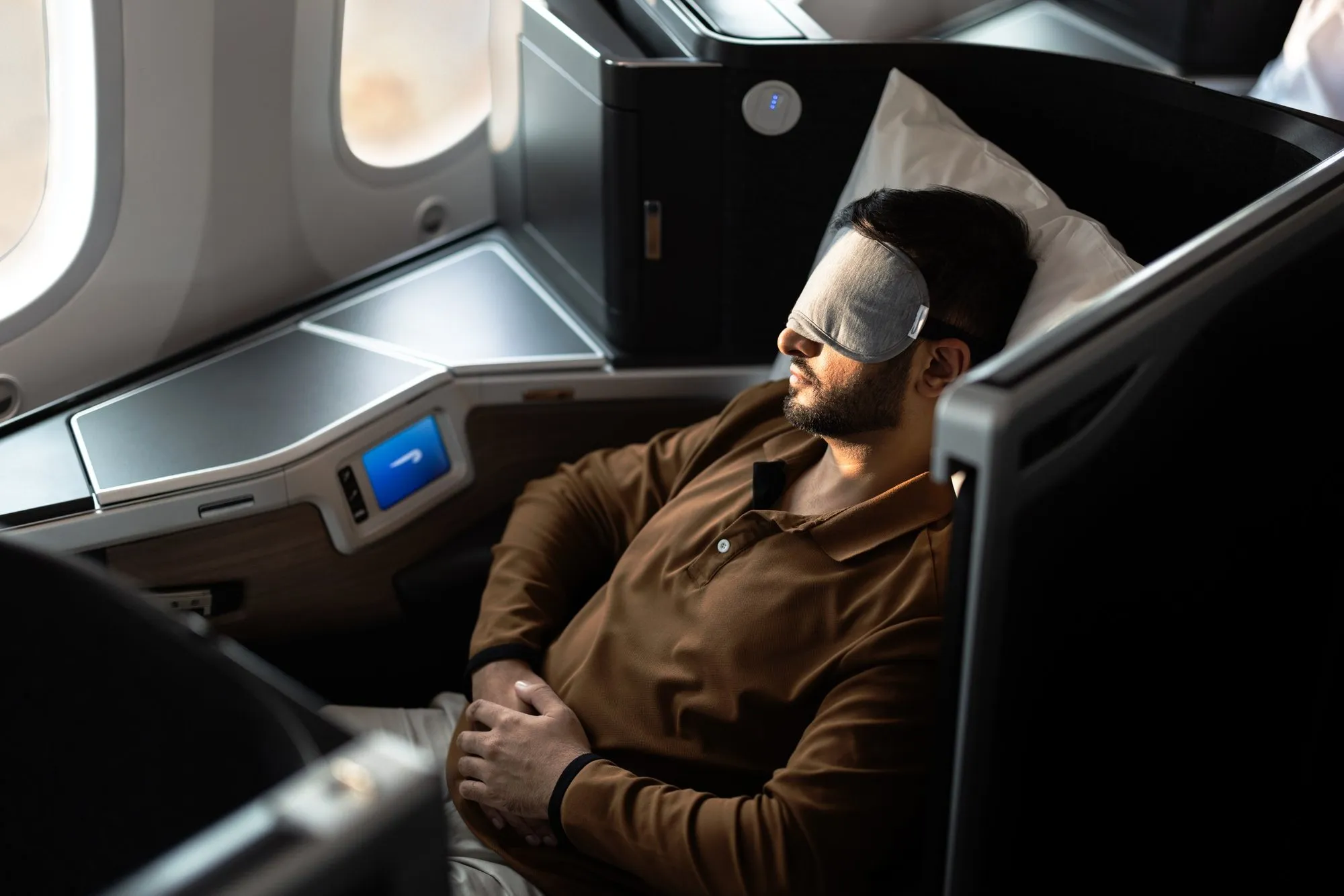 A passenger asleep in an eye mask in a Club Suite