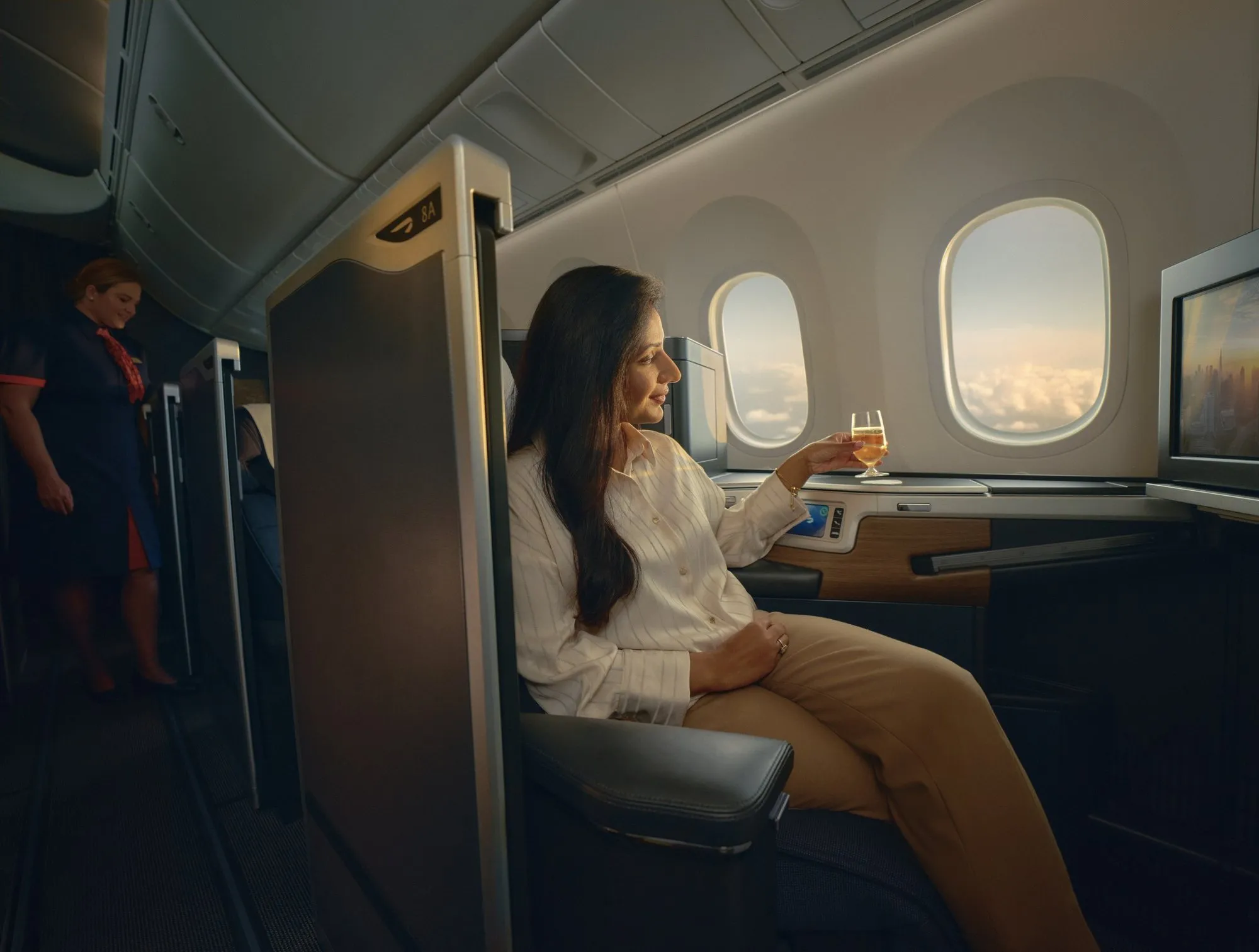 British Airways business class: a passenger with a drink at her window in a Club Suite
