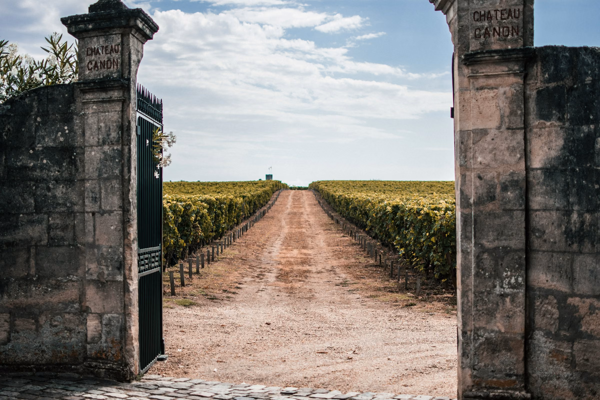 Stone gateposts opening onto a vineyard track at a Bordeaux château