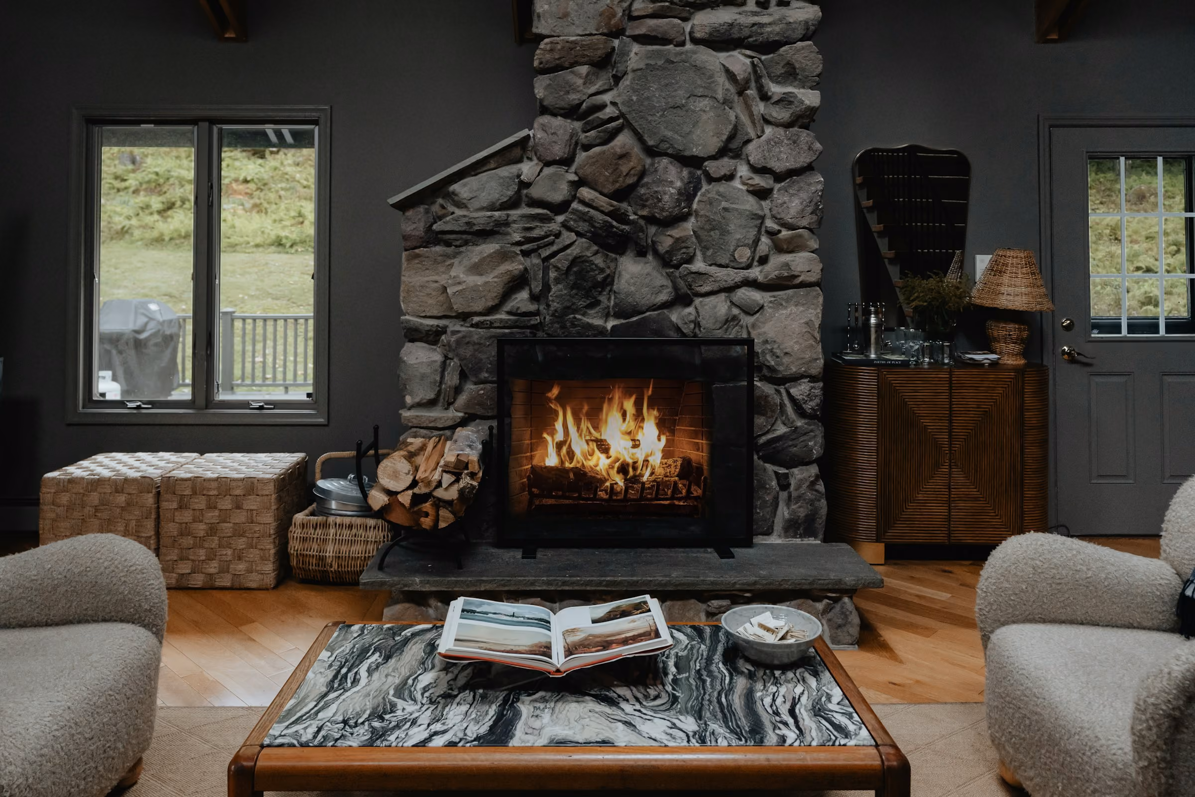 A stone fireplace with a log fire in a chalet living room
