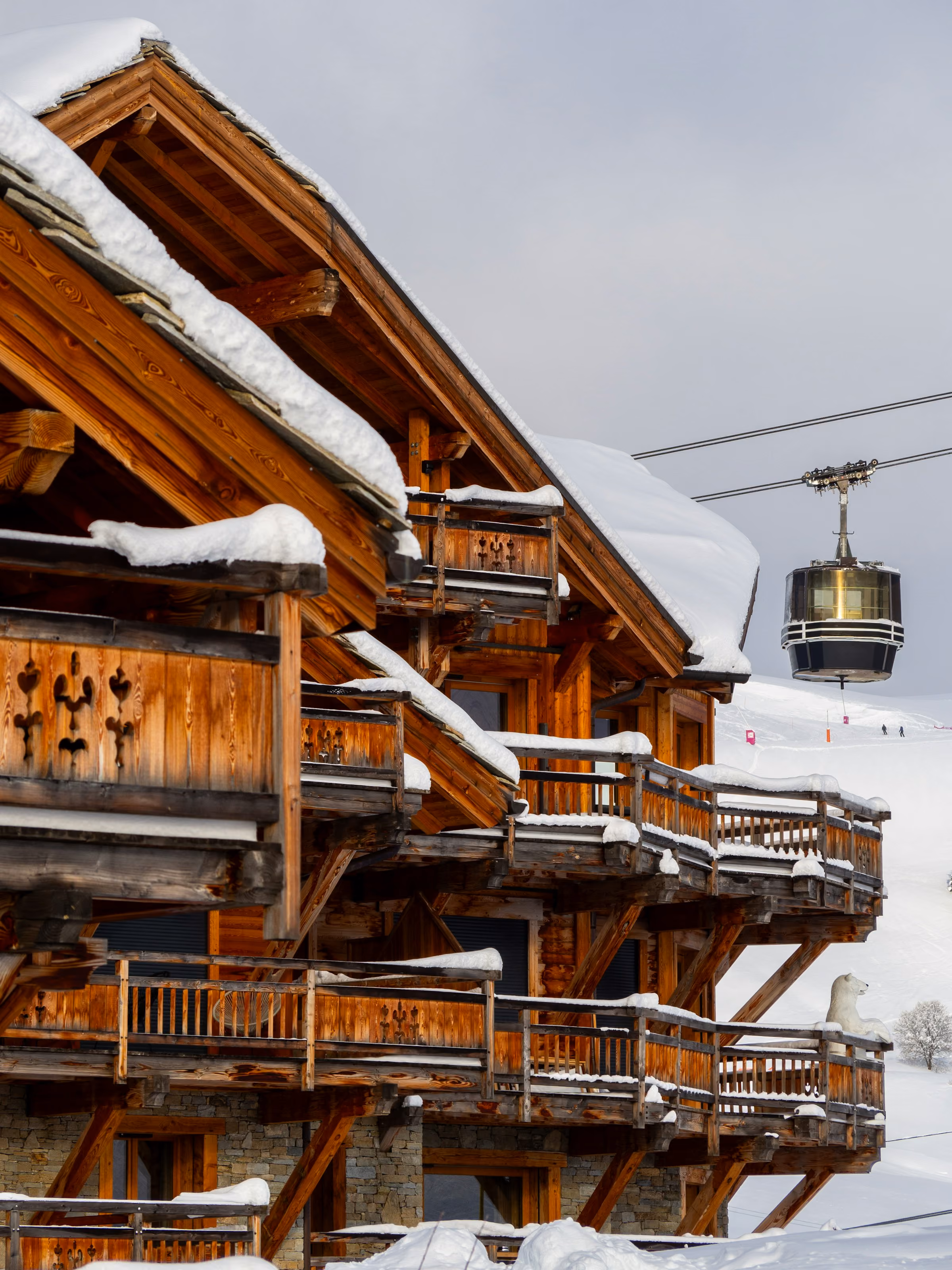 A carved wooden luxury chalet by a cable car in the snow