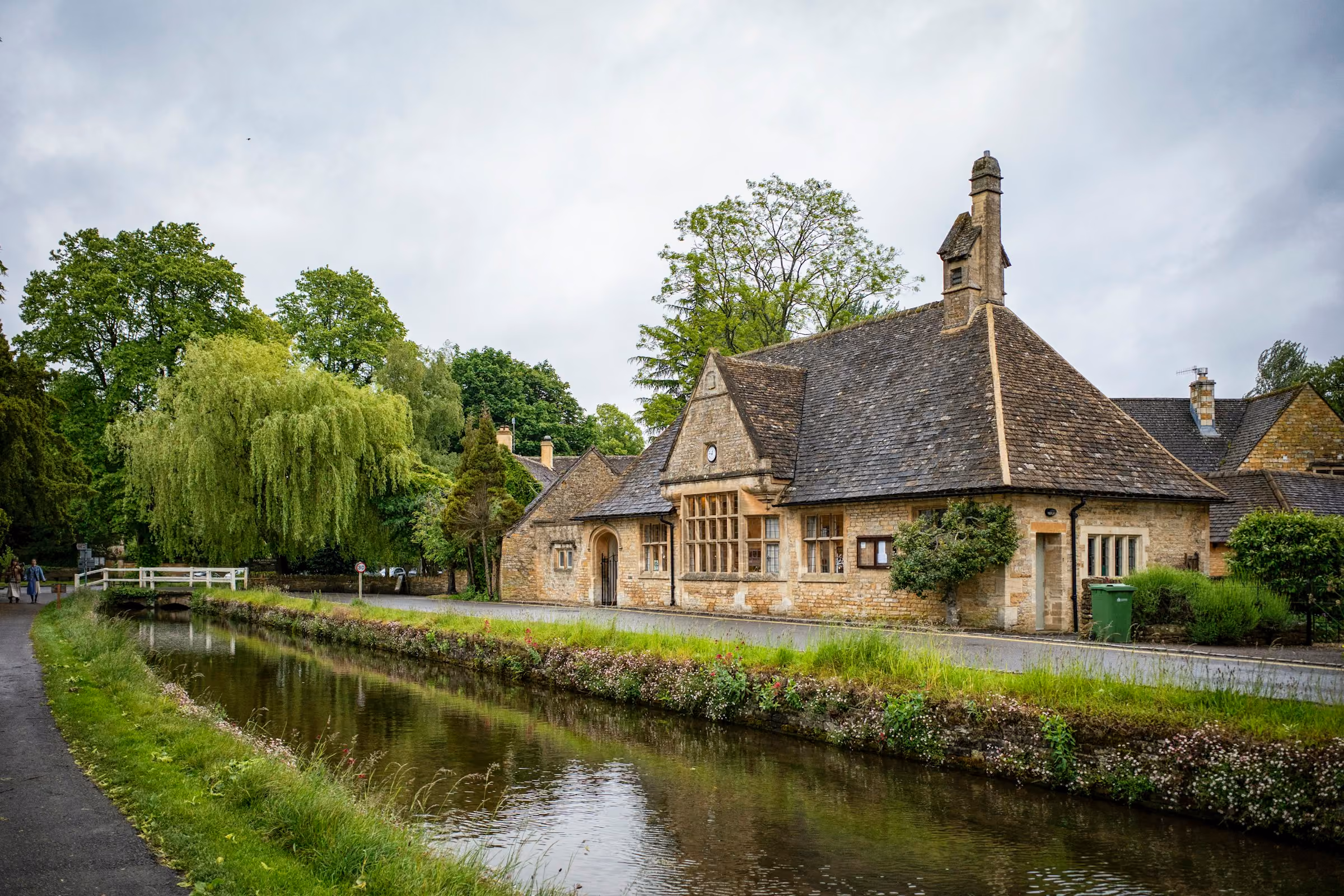 A Cotswold stone house on a quiet riverbank with willows