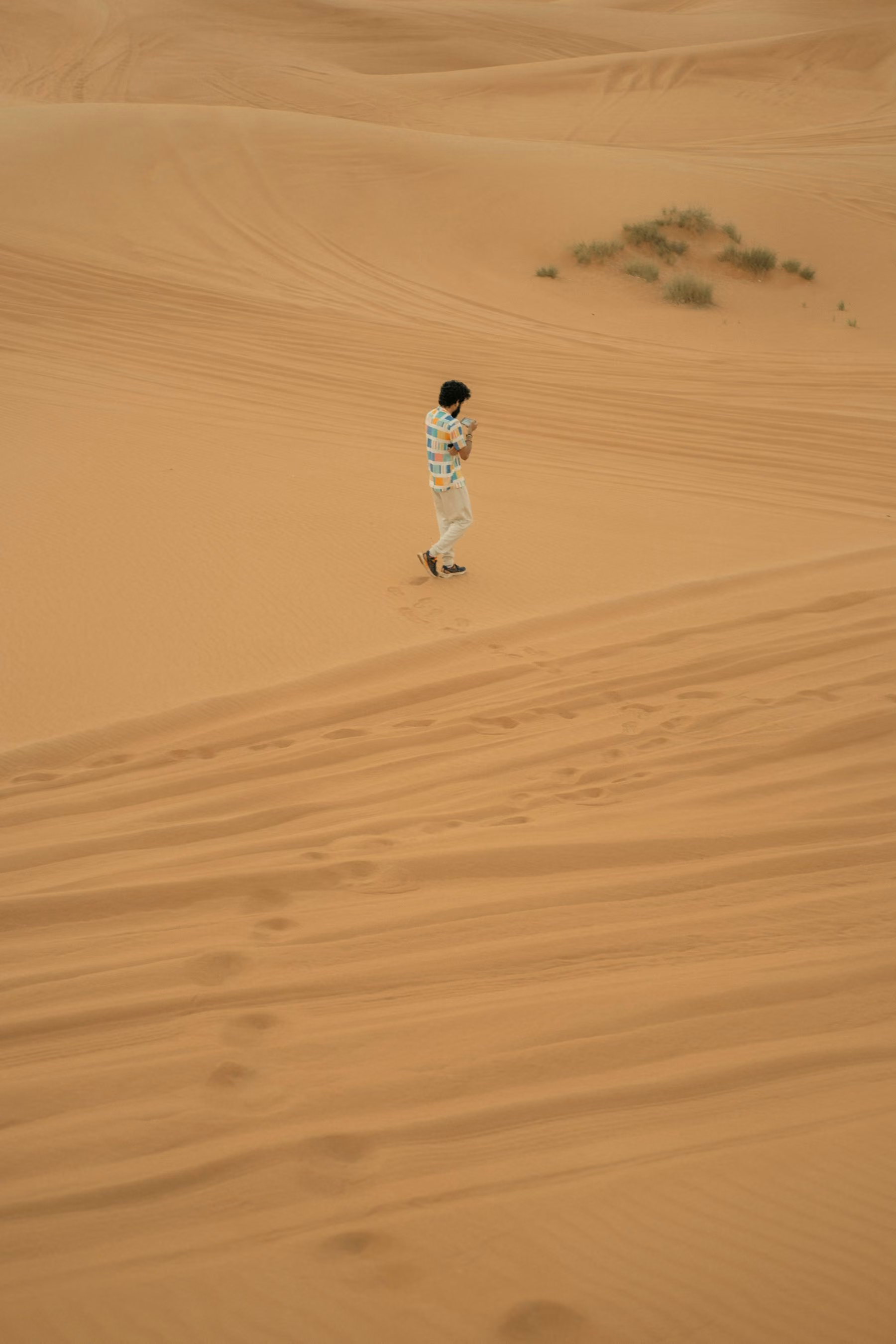 A lone walker crossing rippled red sand dunes in the desert outside Dubai