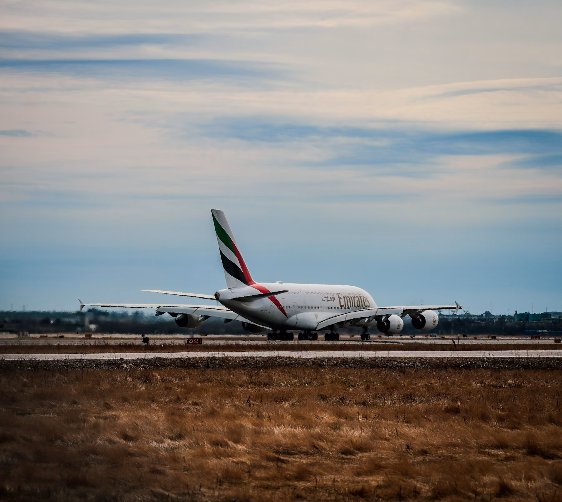 An Emirates Airbus A380 on the runway under a pale evening sky