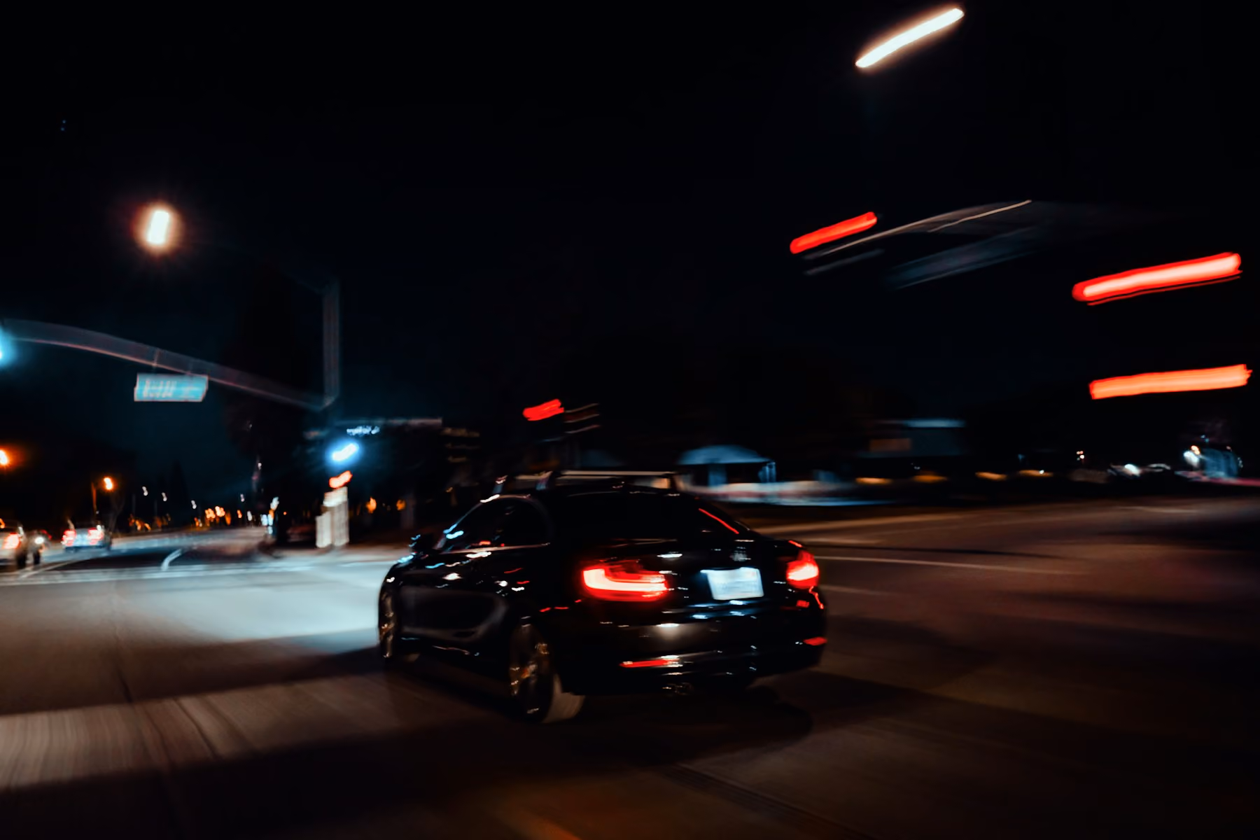 A dark saloon car on a city street at night, the start of an Emirates business class journey