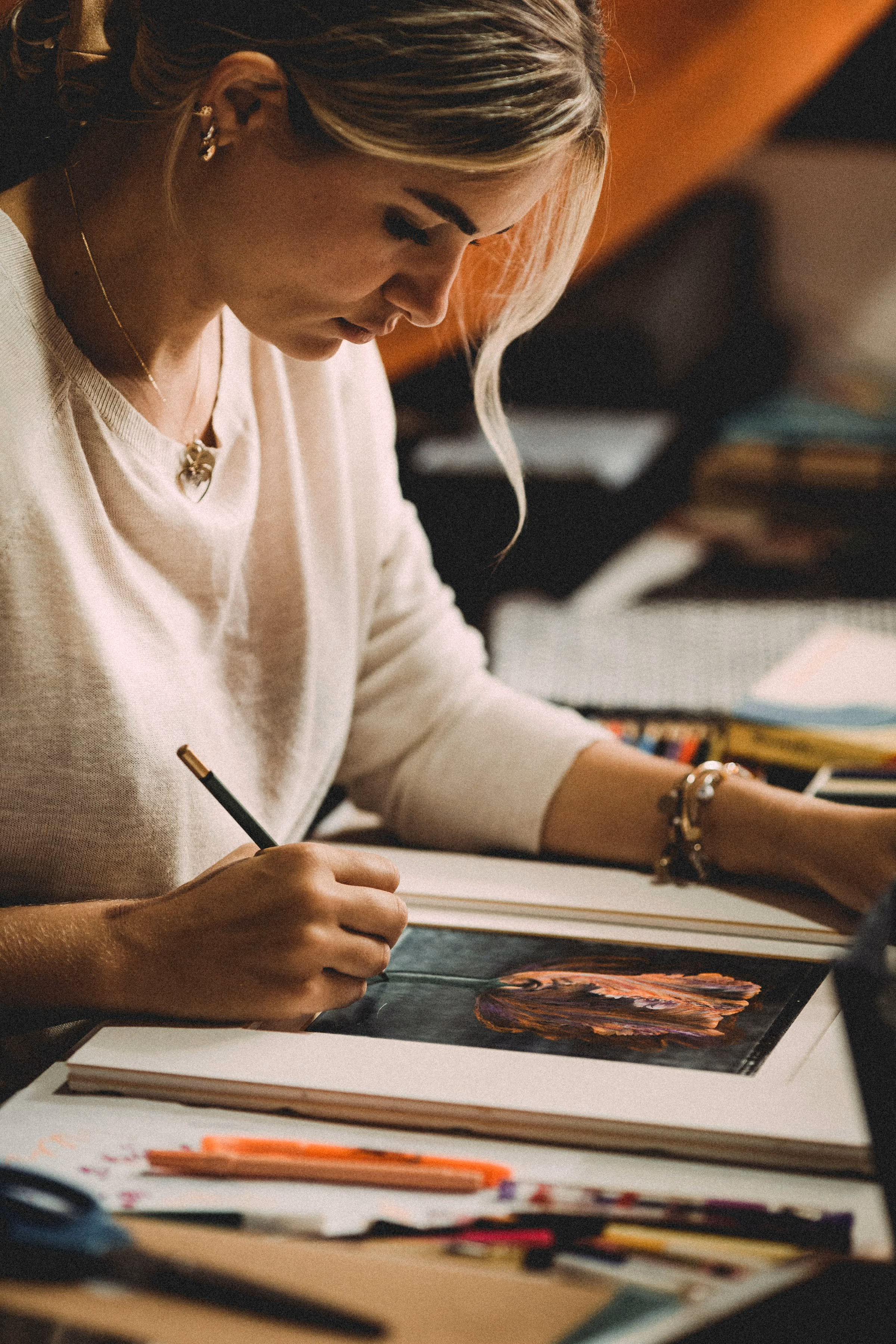 An artist working on a pastel drawing at a desk