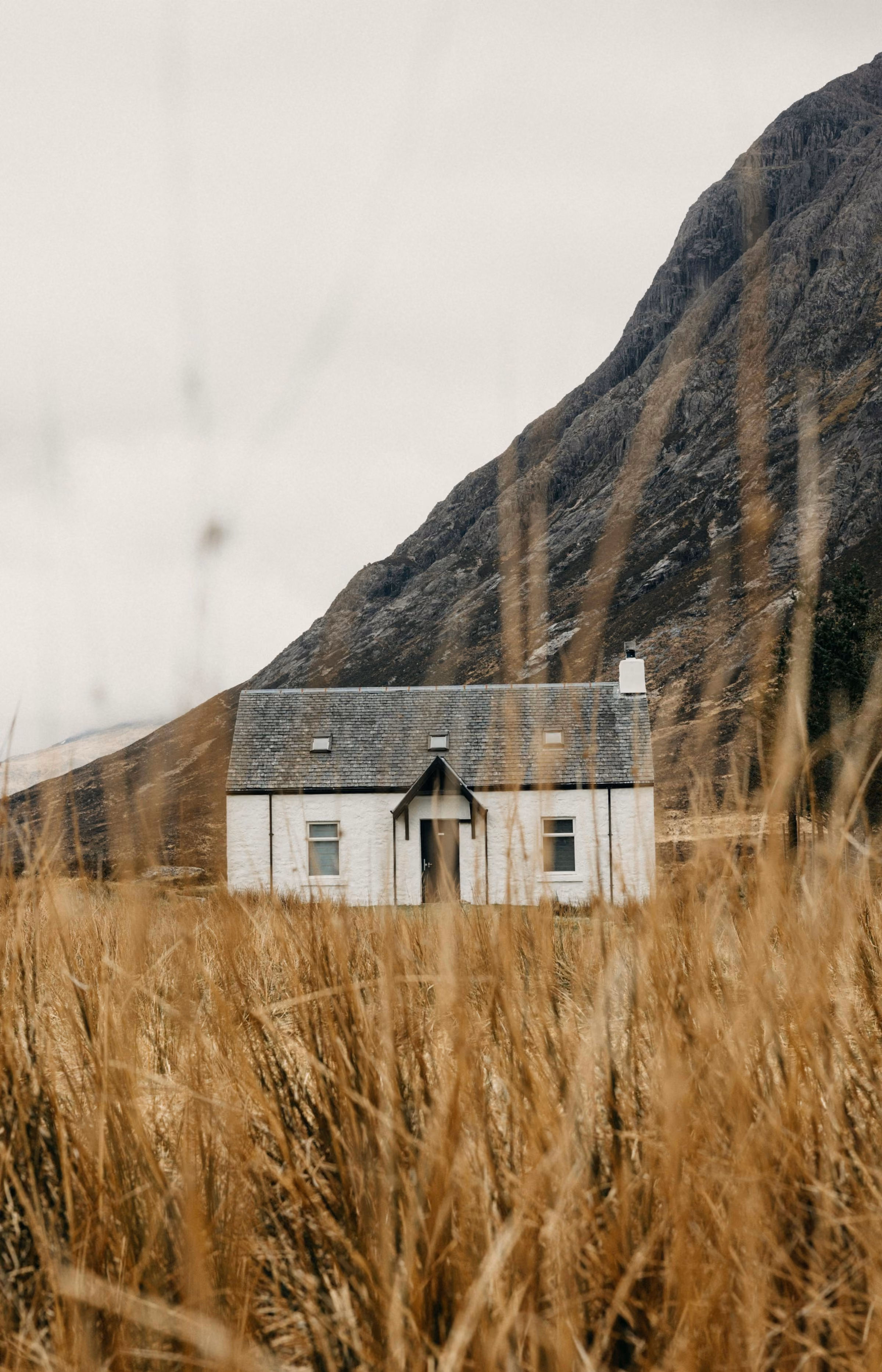 A white cottage below a Highland hillside