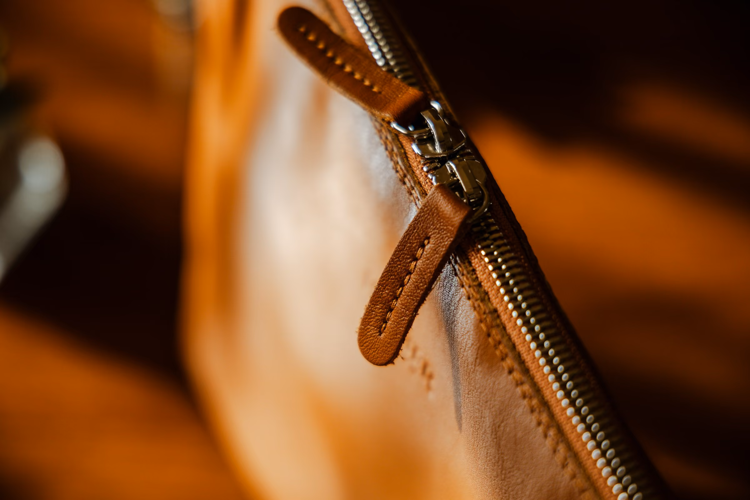 Stitching and a zip pull on a tan leather bag