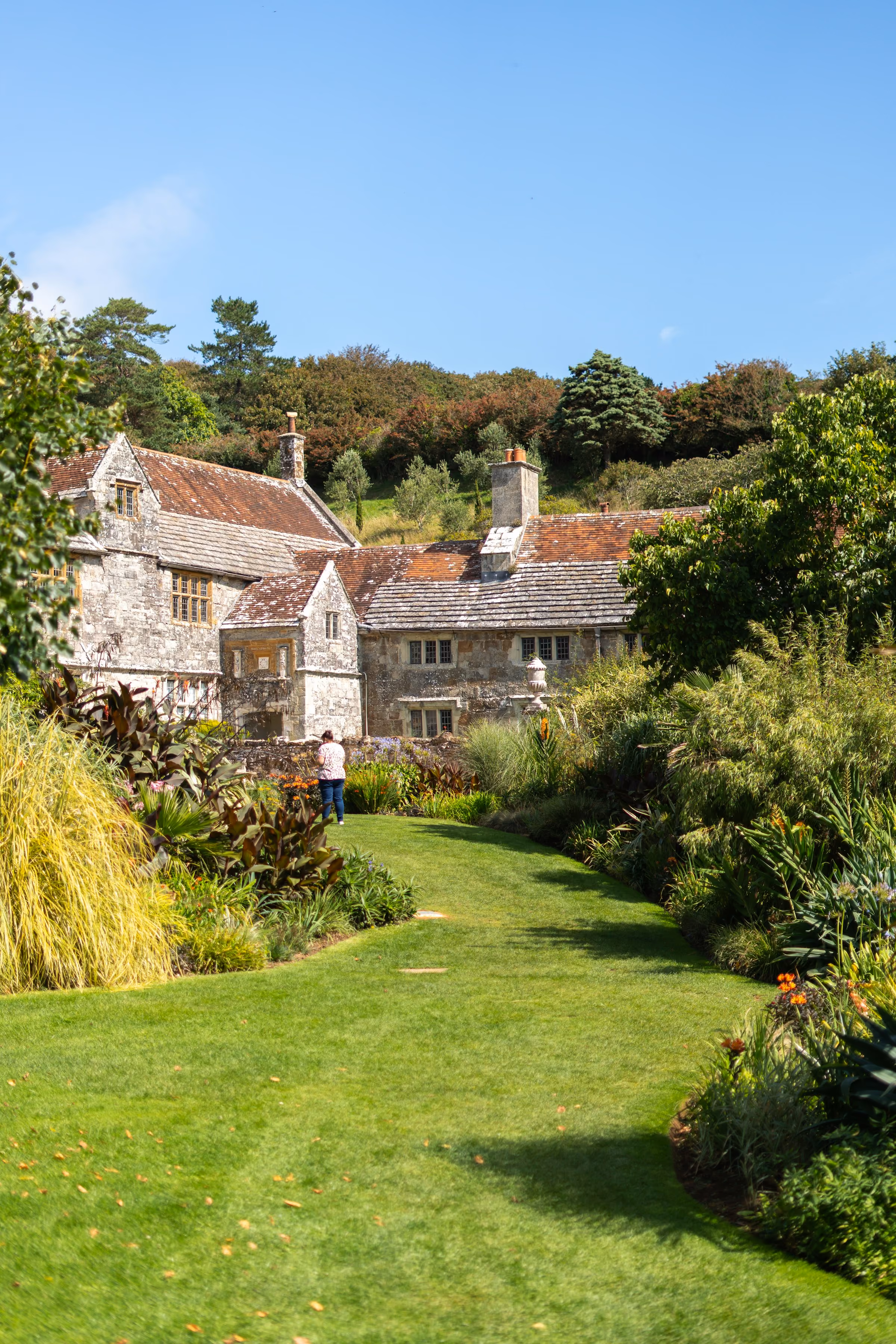 An old manor house above a lawn and borders