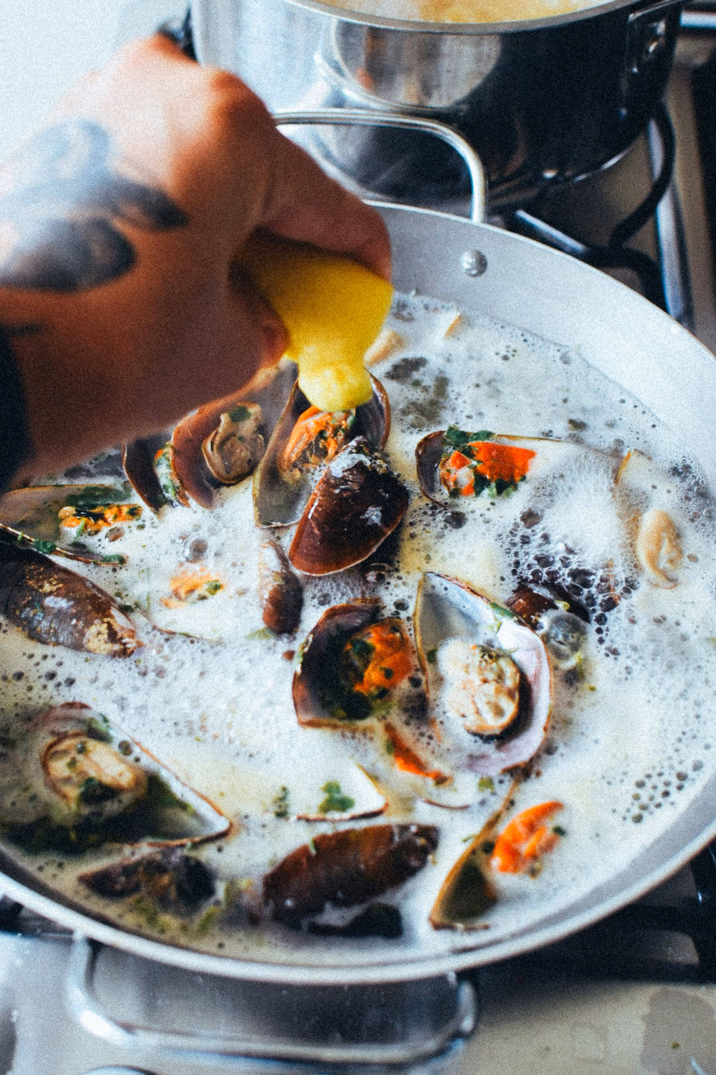 Lemon squeezed over mussels and clams in a pan