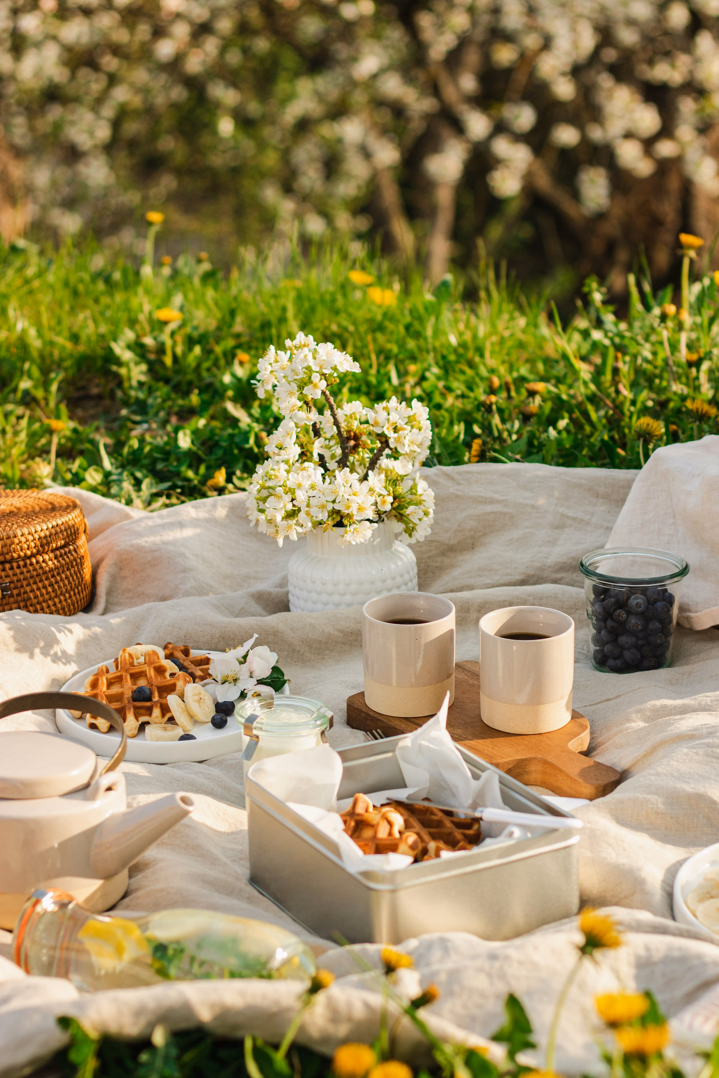 A picnic laid out with flowers on a white blanket