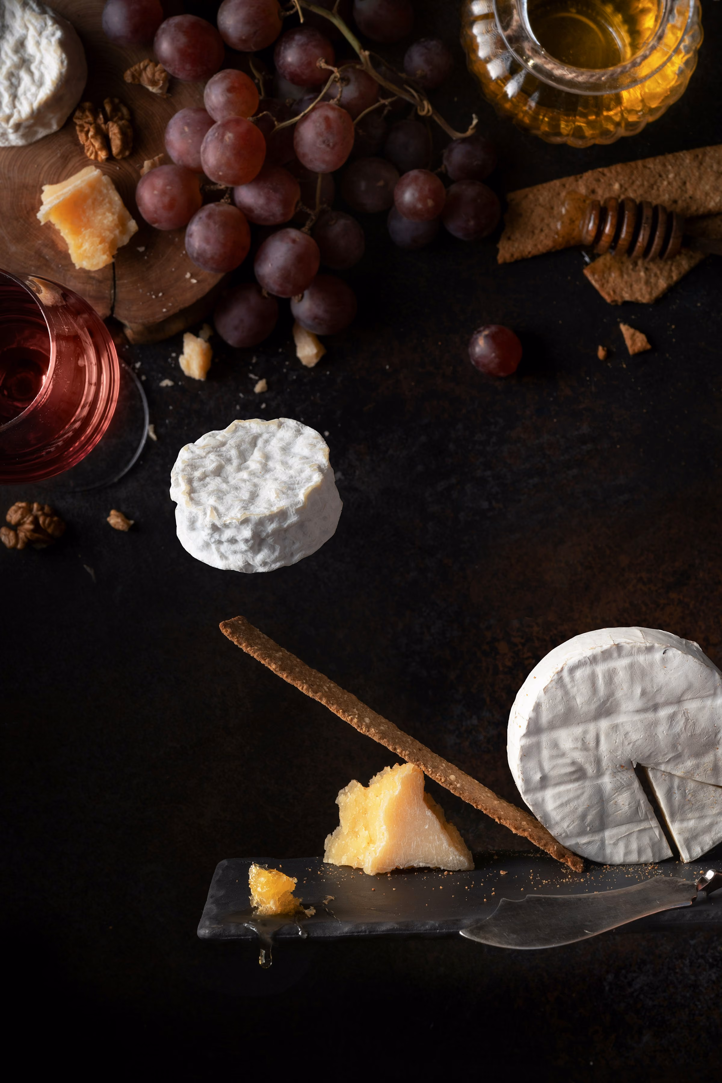 Cheese, grapes and a glass on a dark table