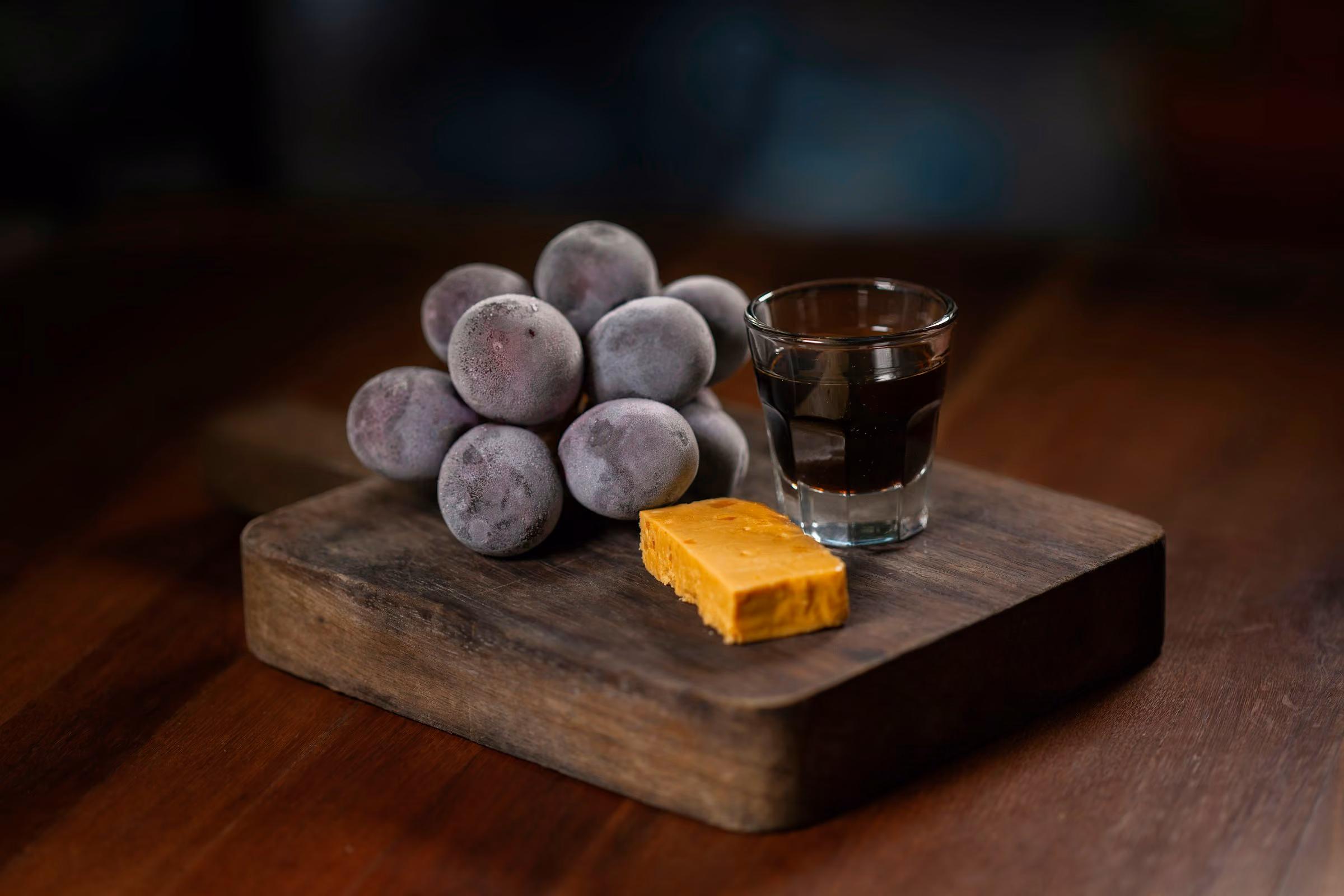 A small glass of port with figs and cheese on a wooden board