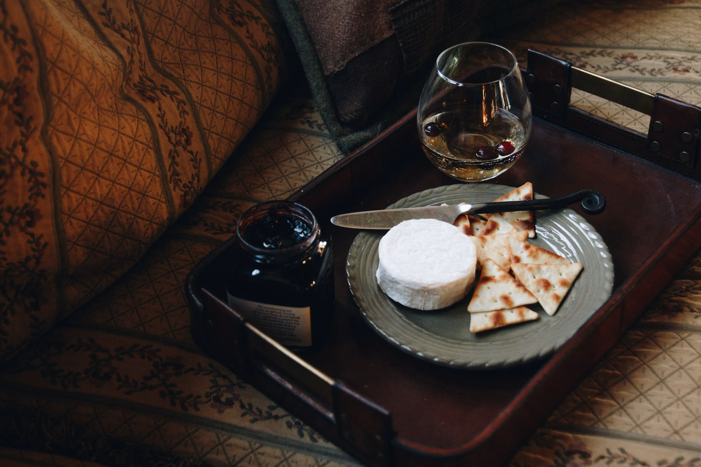 A glass of port on a tray with soft cheese