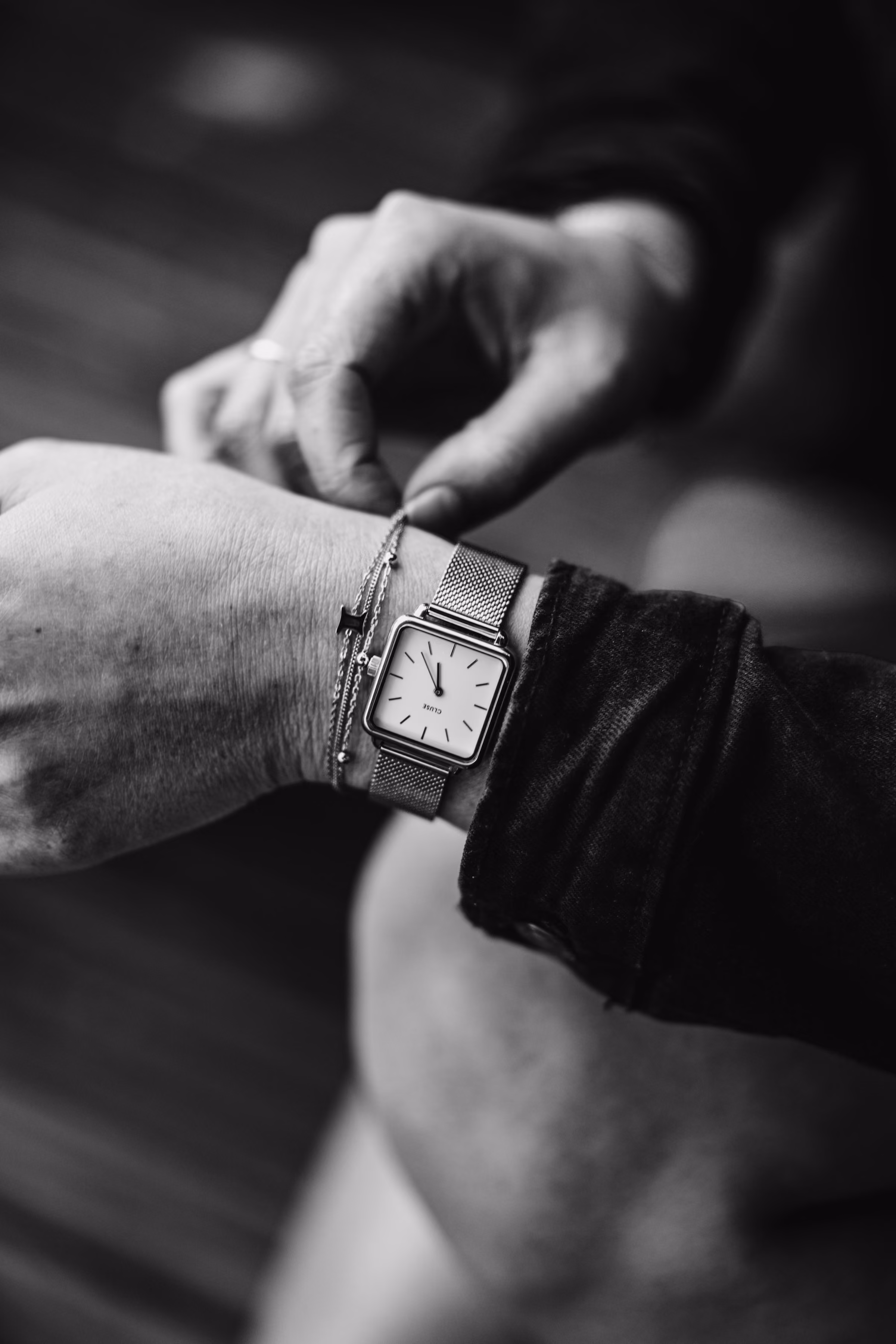 A rectangular watch on a mesh strap, in black and white