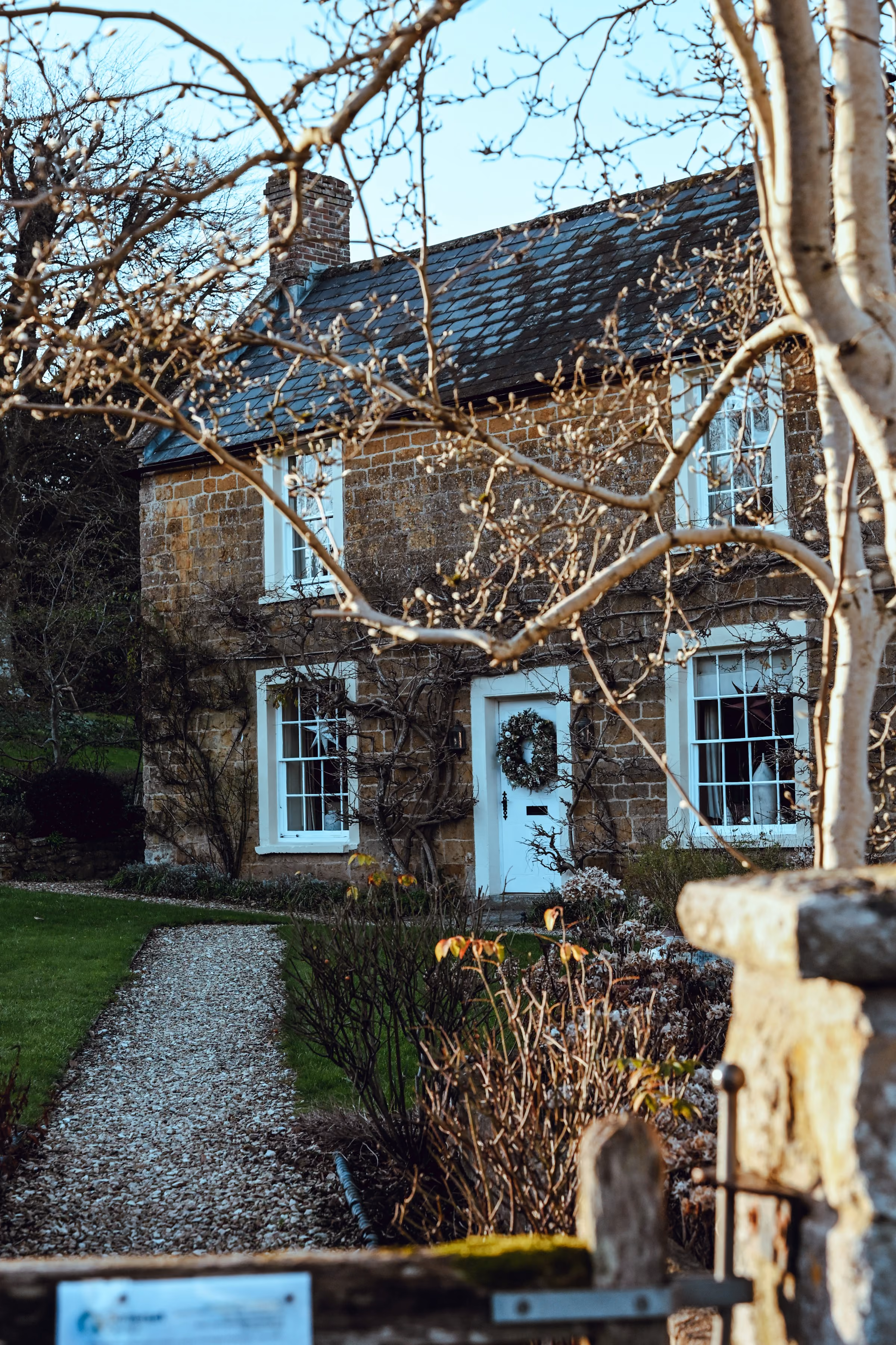 A stone cottage with a blue door and gravel path