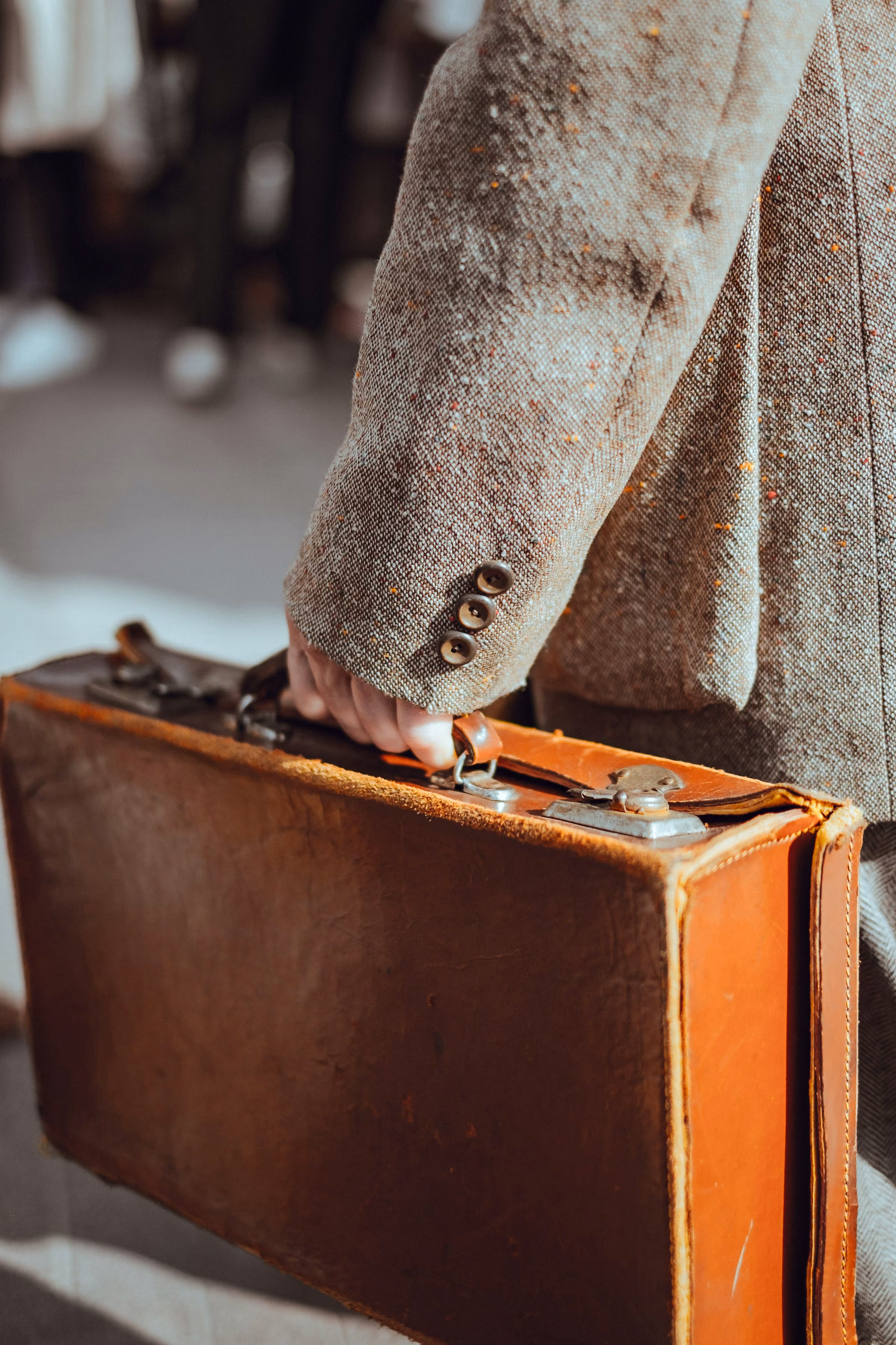 A traveller carrying a brown leather suitcase