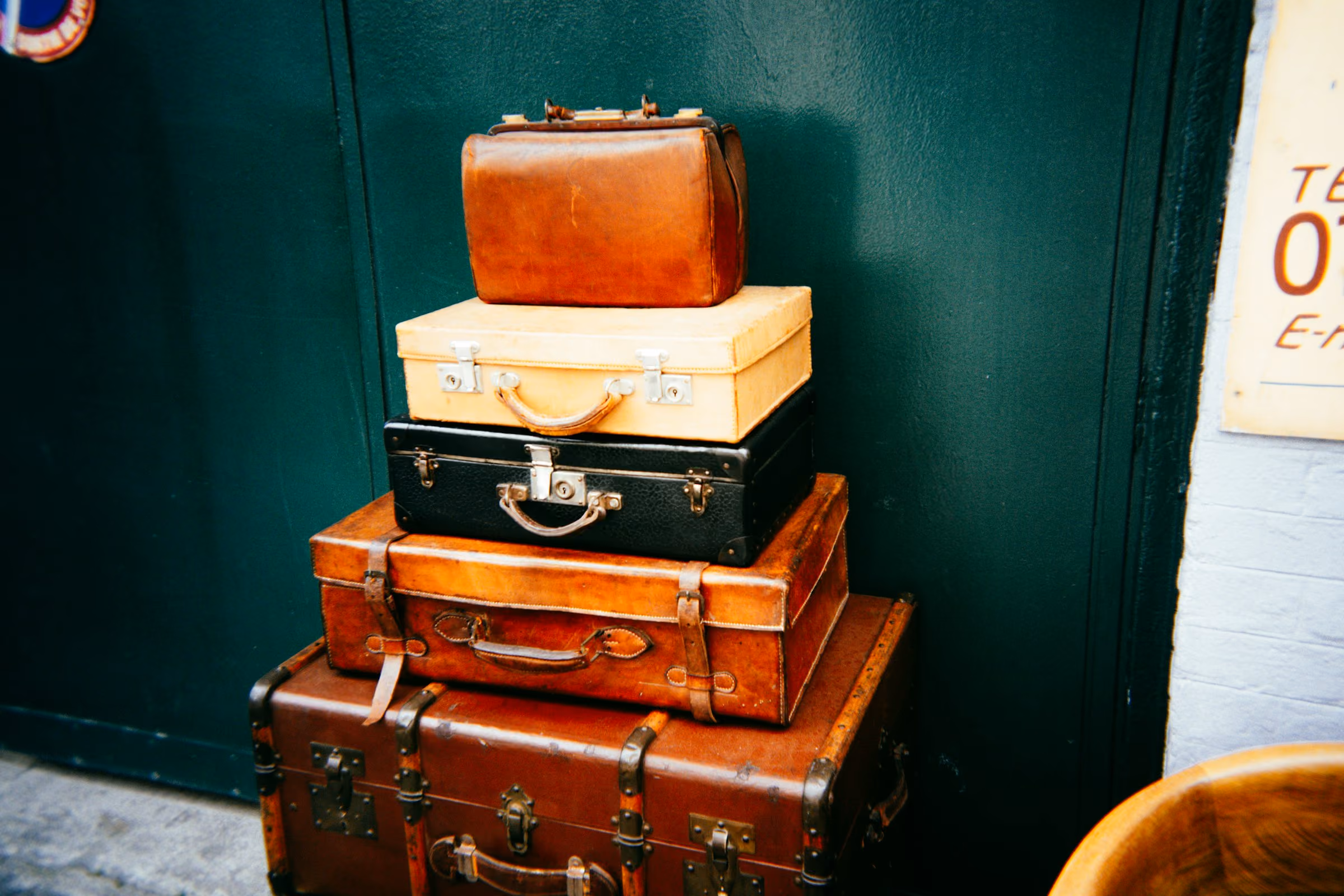 A stack of vintage cases against a green wall