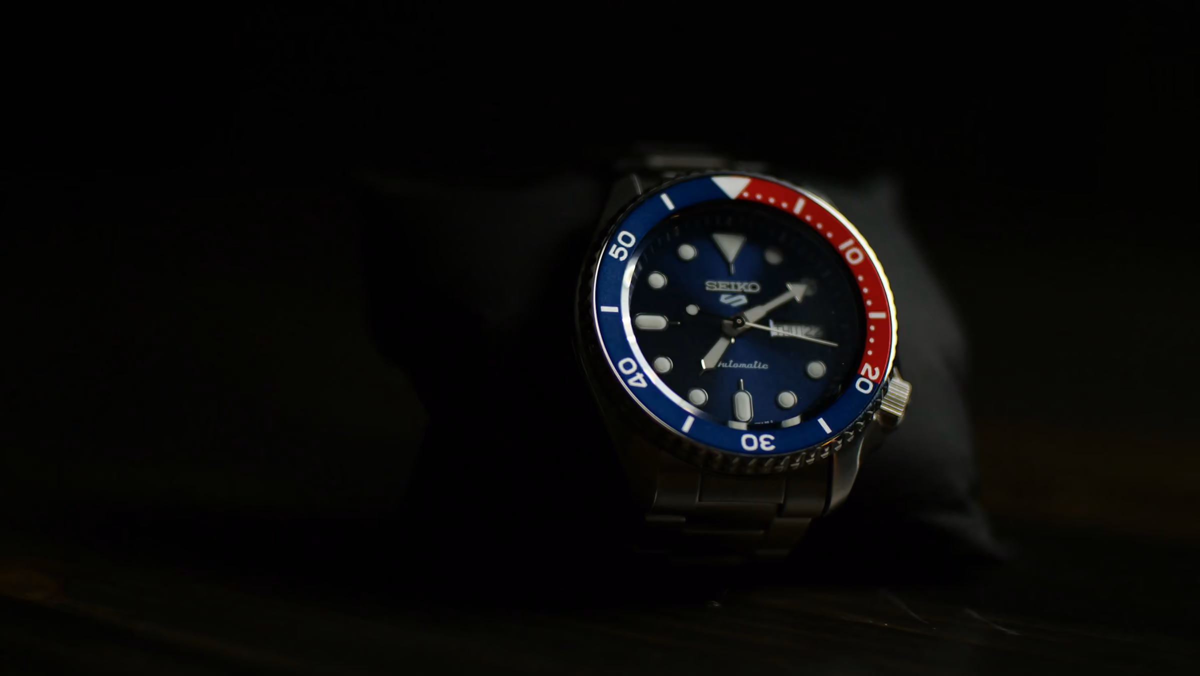 A watch with a red and blue bezel on a dark background