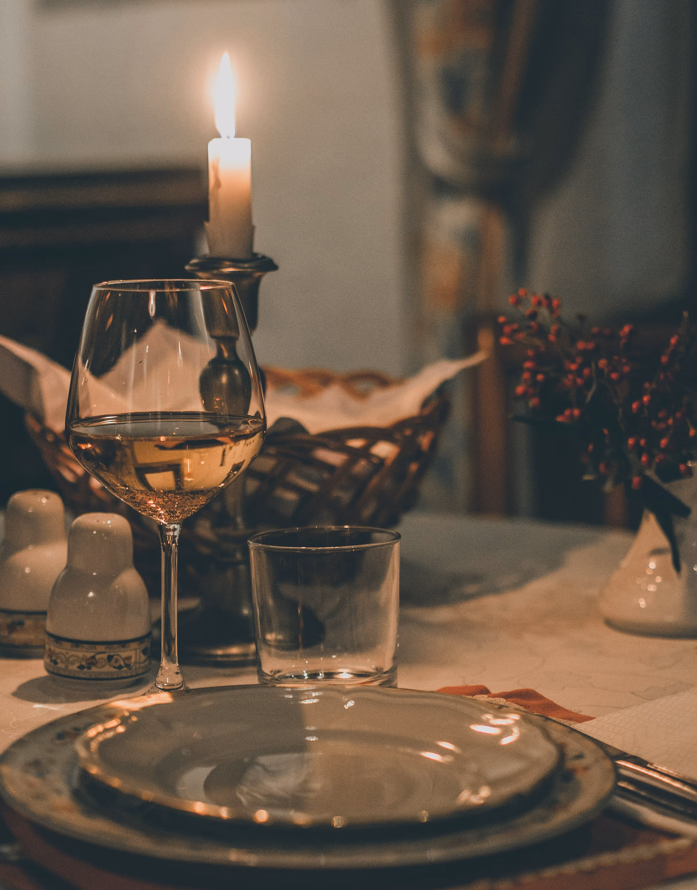 A candle and a glass of wine on a laid table