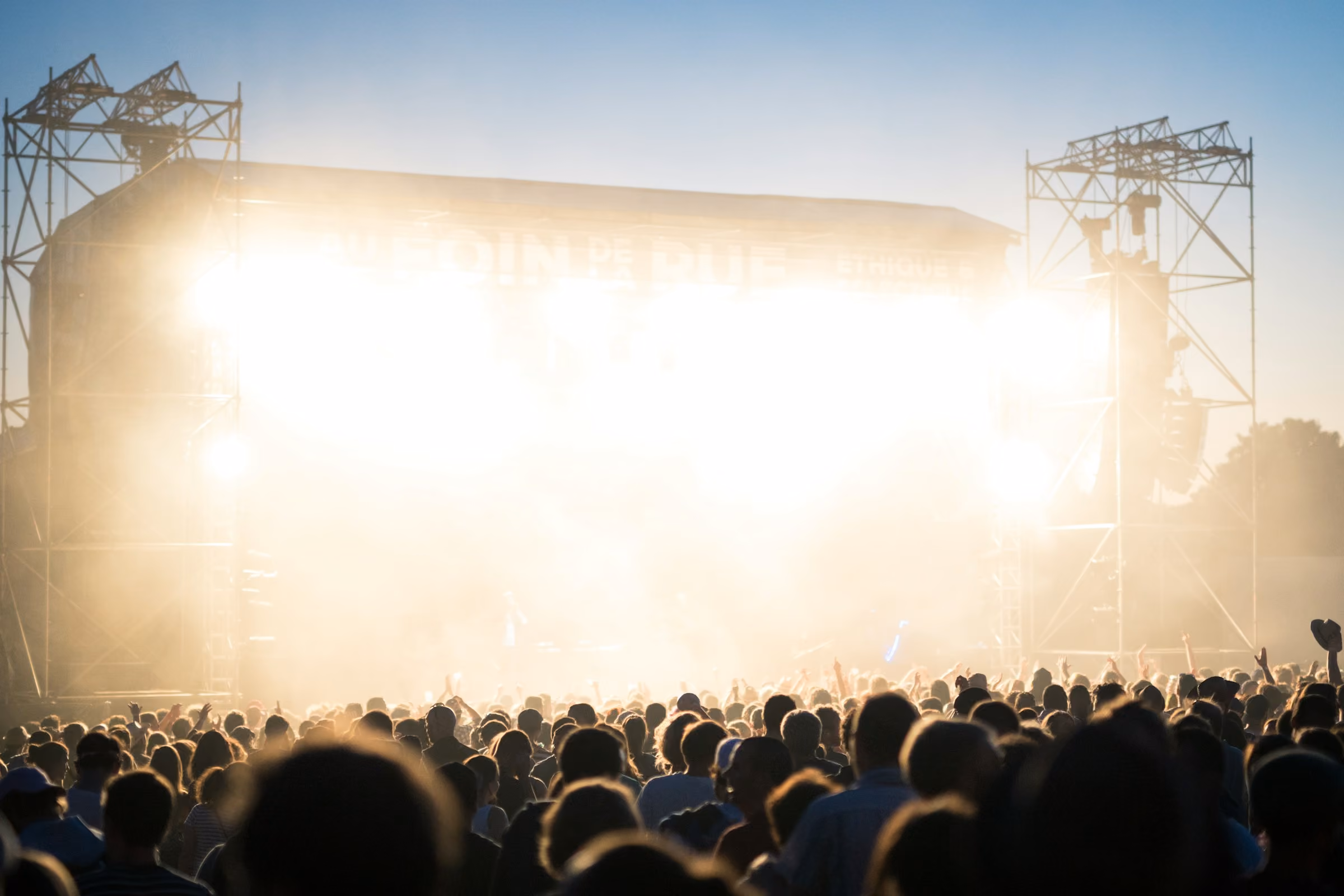 A crowd at an outdoor concert as the sun sets