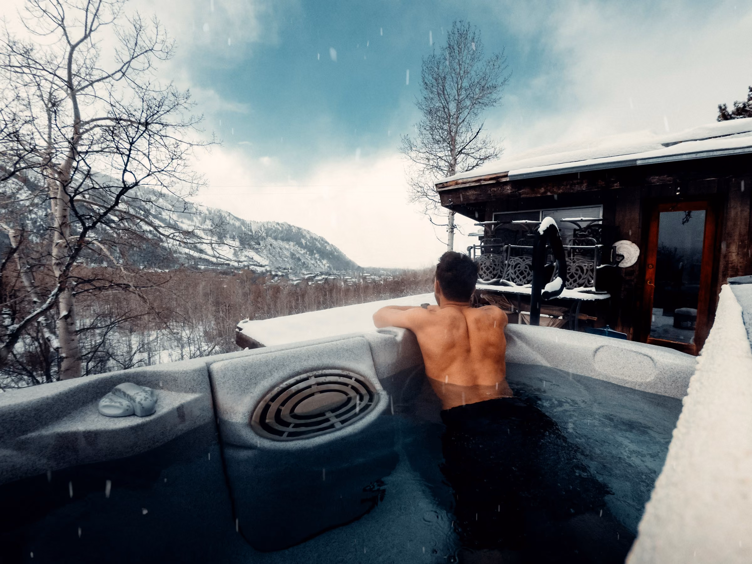 An outdoor hot tub on a snowy terrace with mountain views