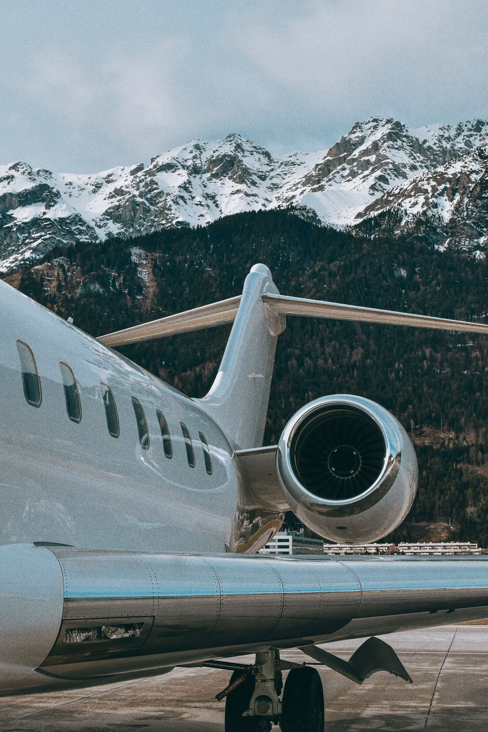 The wing and engine of a private jet, snowy mountains behind
