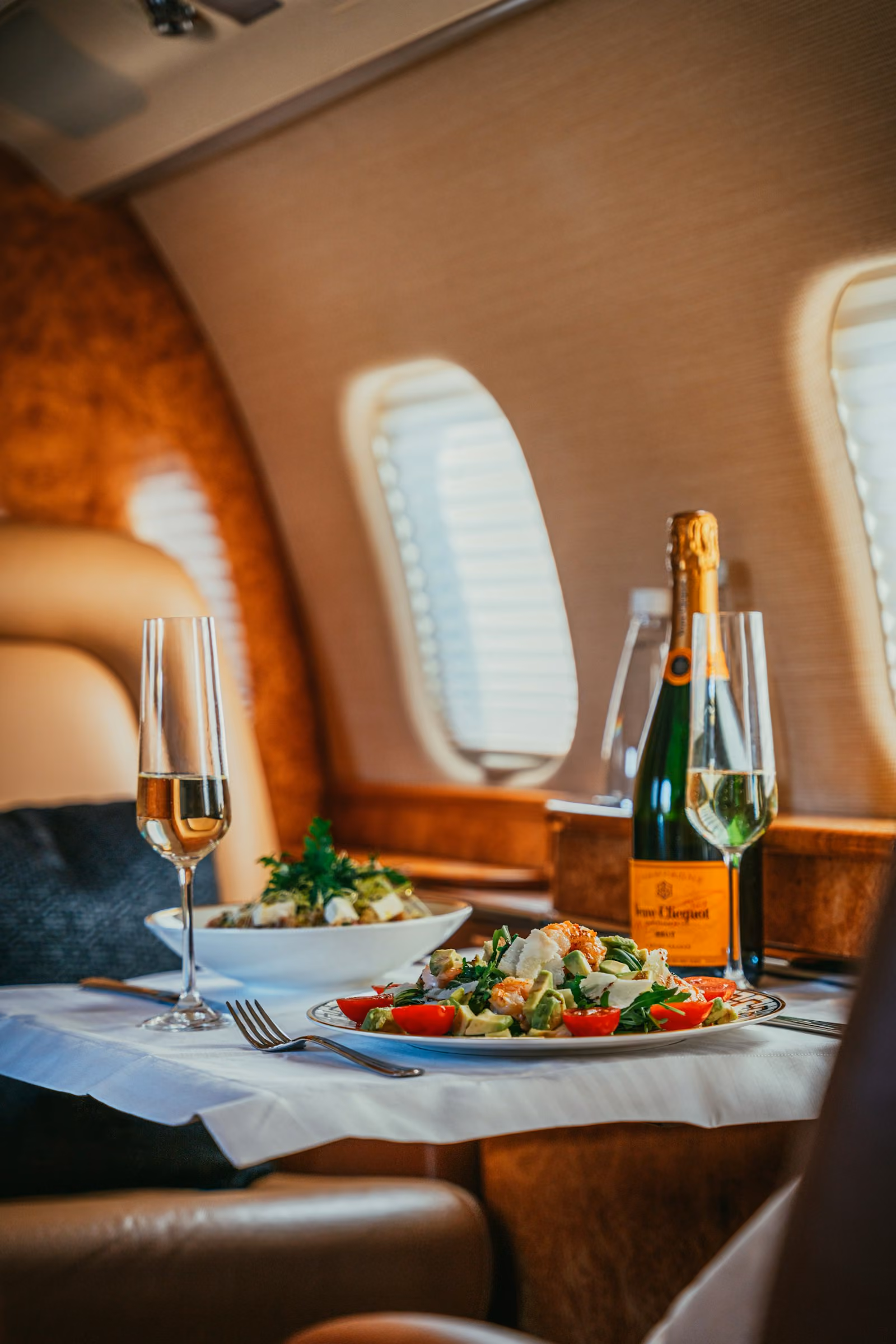 A table laid with food and wine by the window of a private jet
