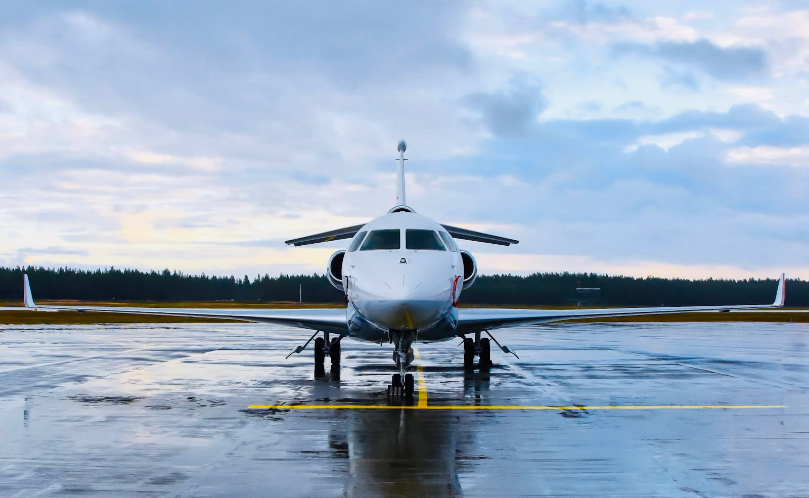 A private jet alone on a wet runway under a grey sky