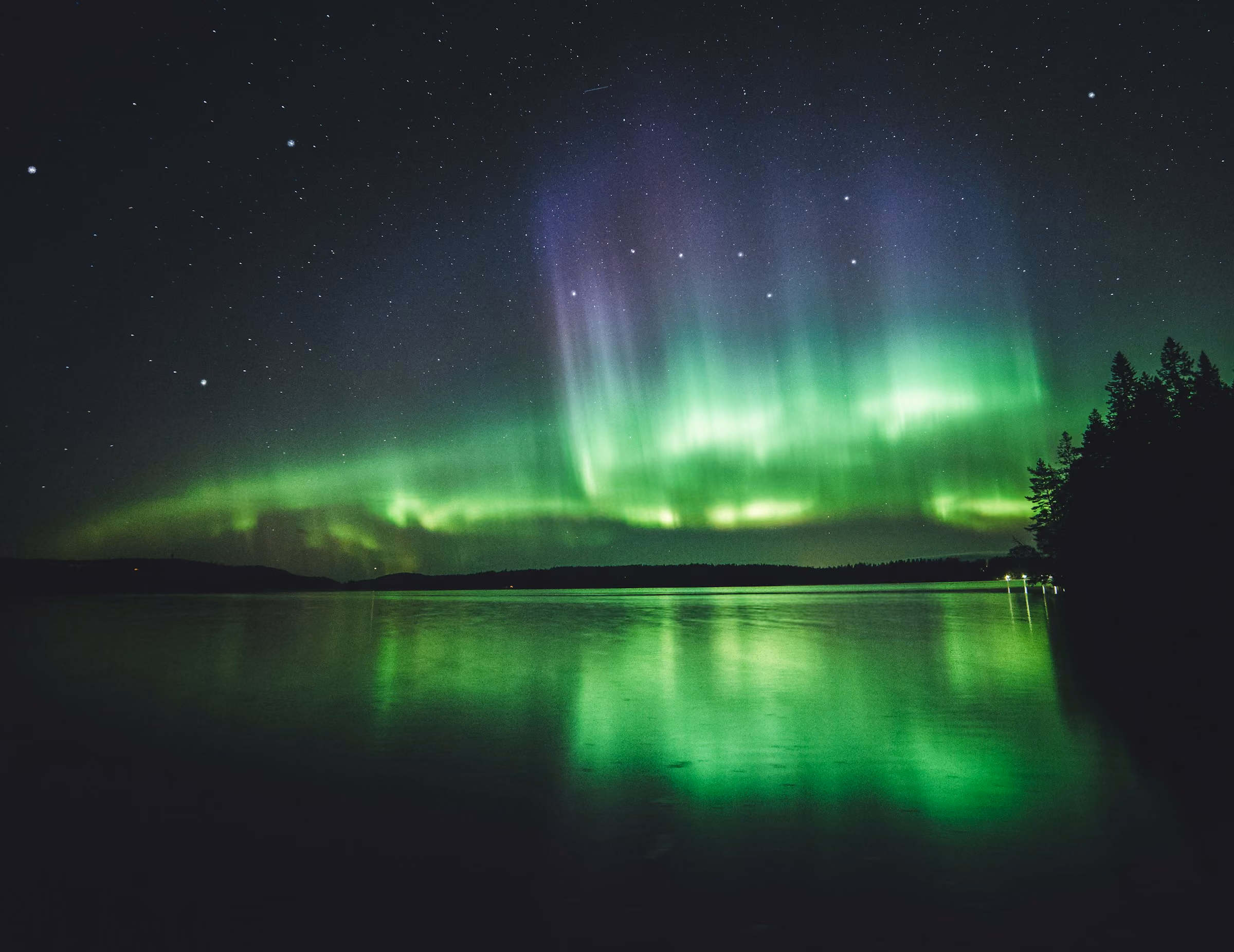 Green northern lights reflected in a still lake in Lapland