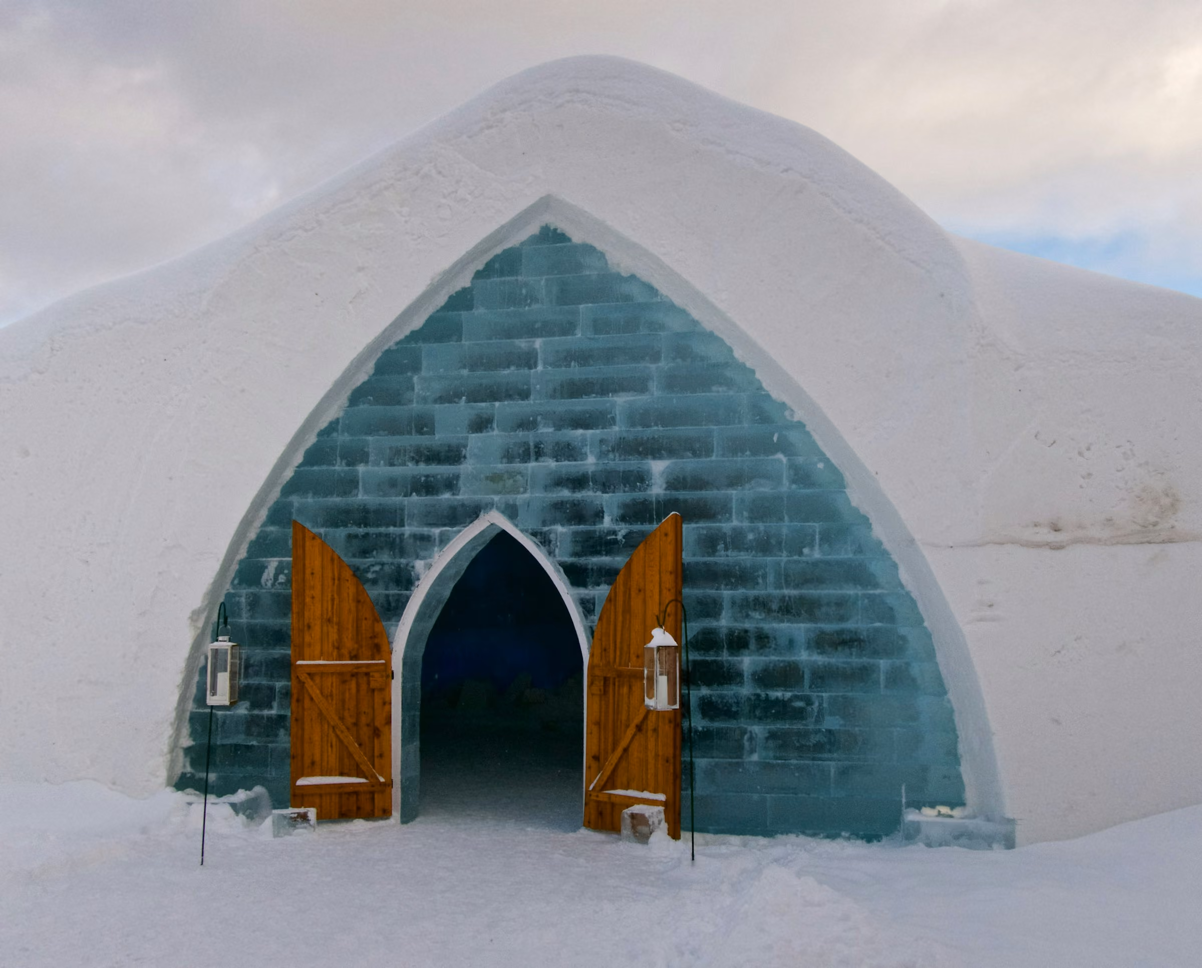 The arched ice-block entrance of an ice hotel with wooden doors