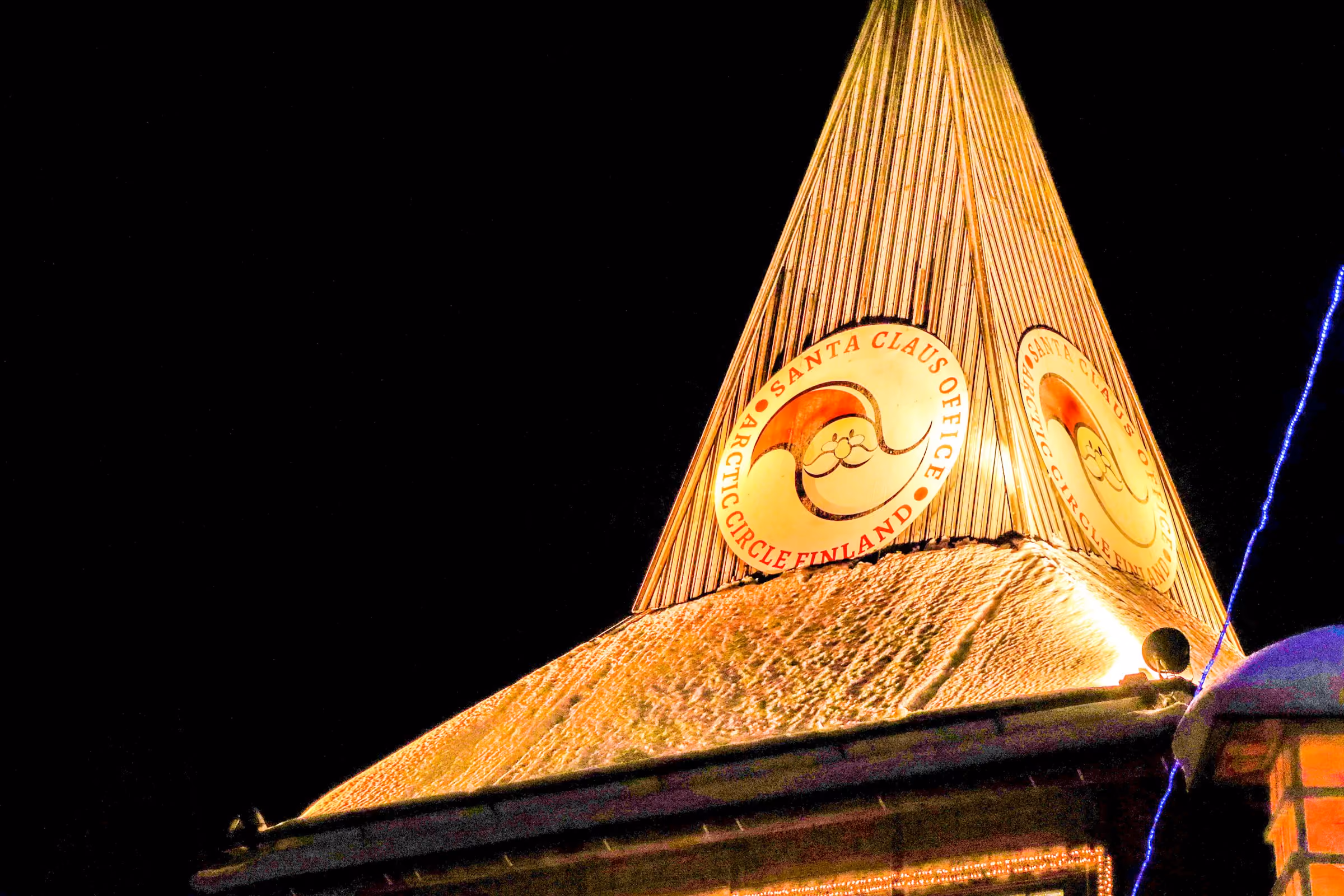 The lit pointed roof of the Santa Claus Office at night in Rovaniemi