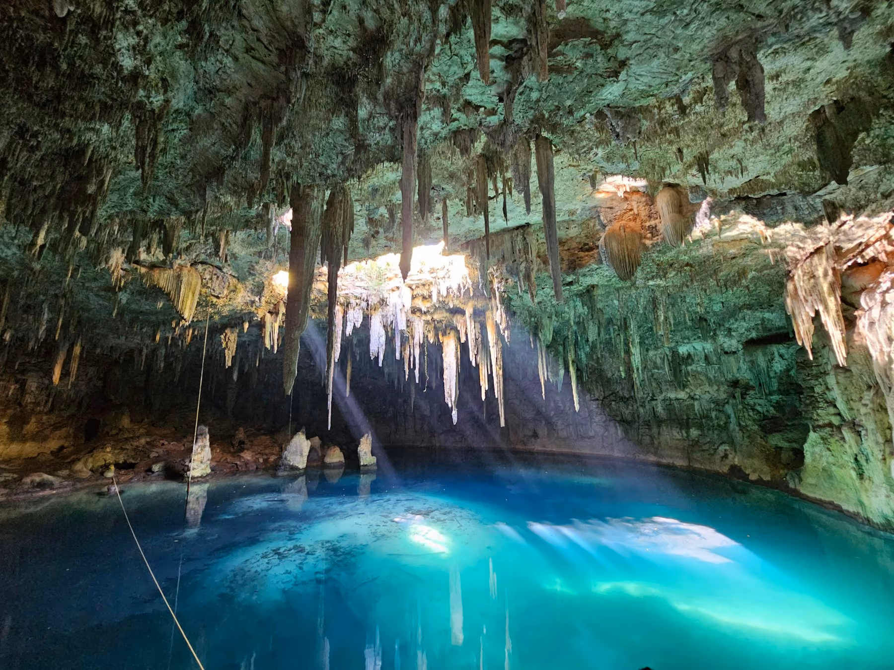 Sunlight falling through a cave roof onto the blue water of a Yucatán cenote
