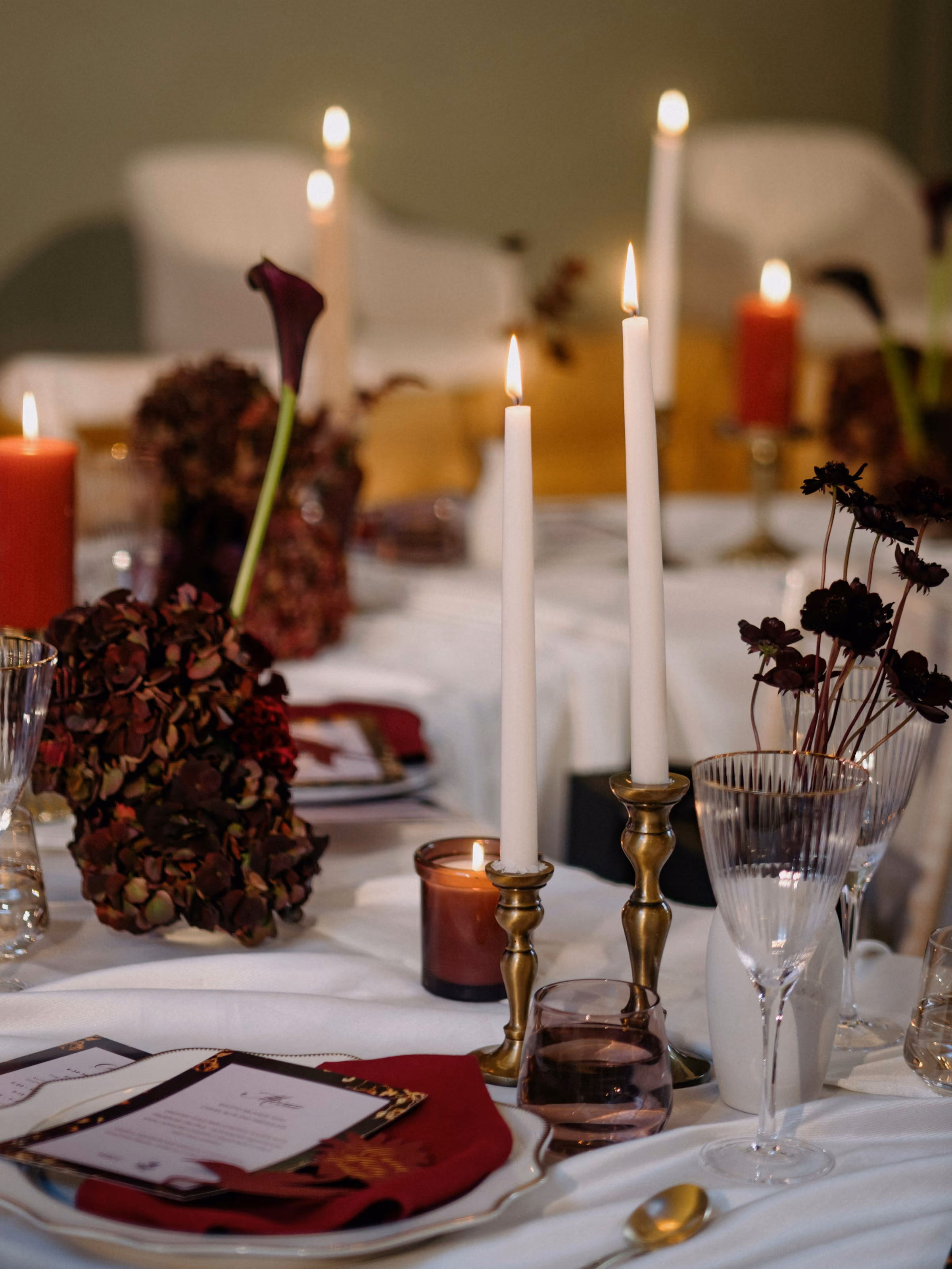 Tall candles and red flowers on a dinner table