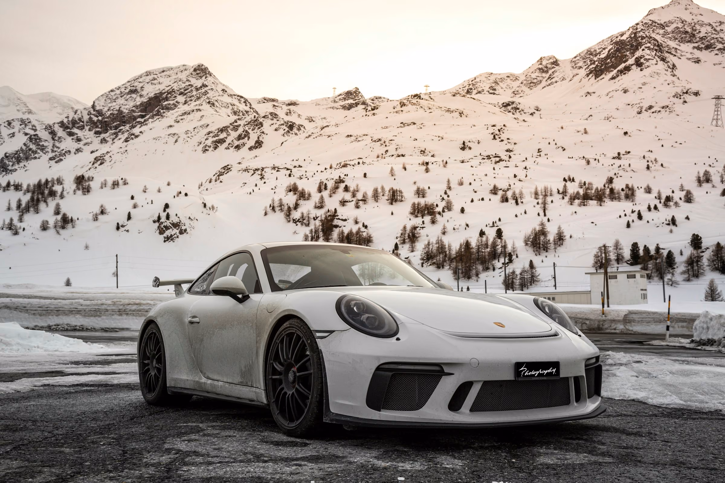 A white Porsche 911 on a snowy mountain road
