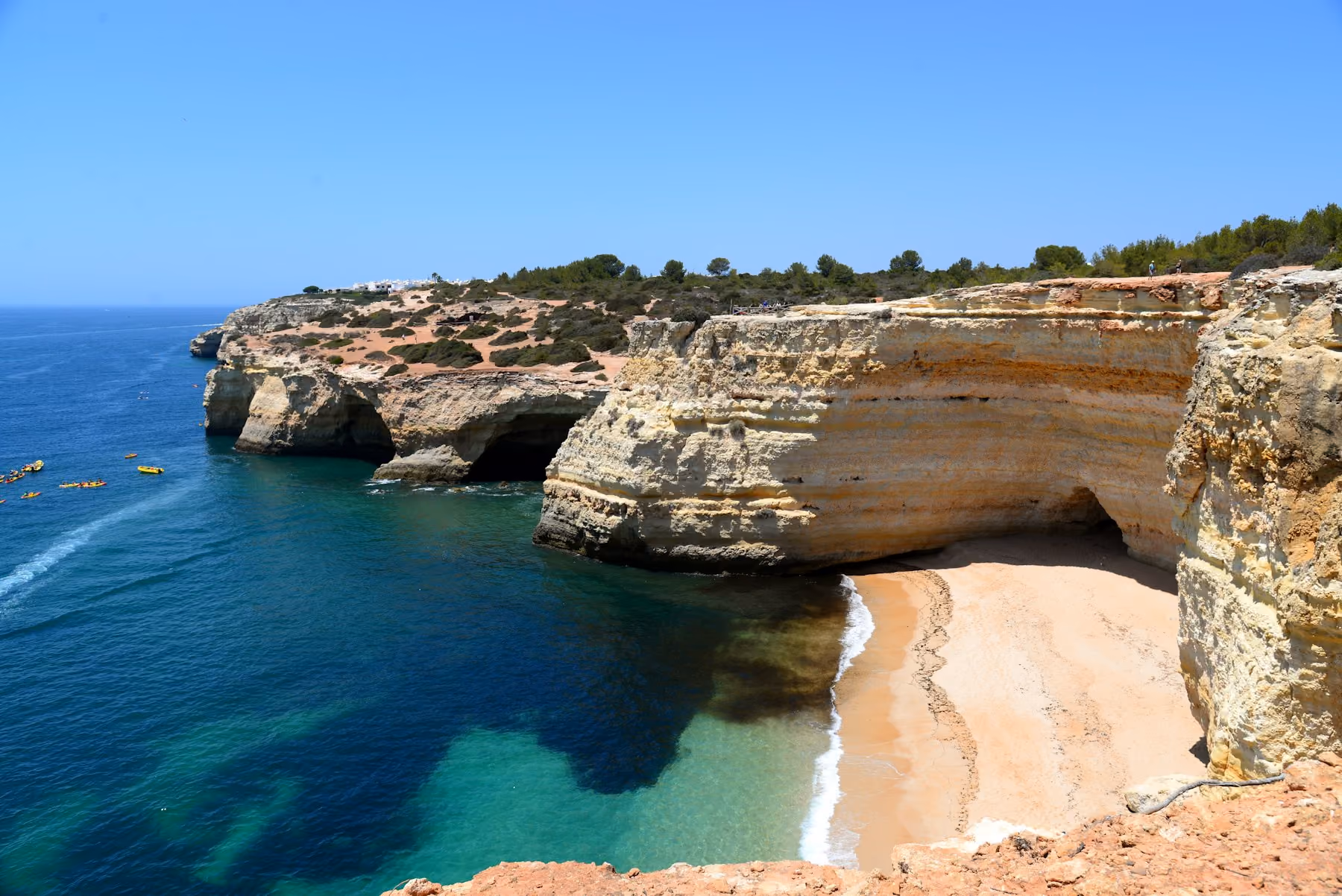 Golden Algarve cliffs above a sheltered cove of clear water: the best time to visit Portugal's beaches is June or September