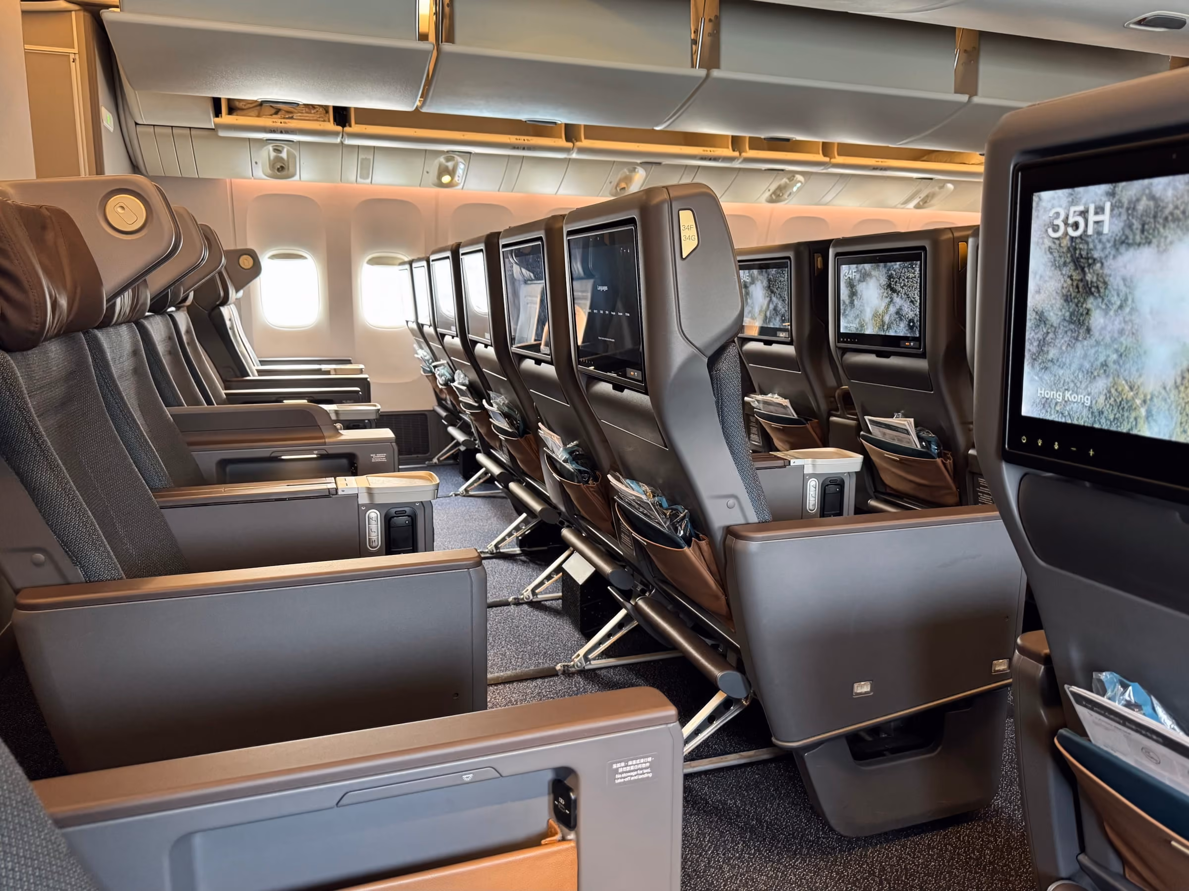 A row of empty premium economy seats with personal screens, seen from the aisle