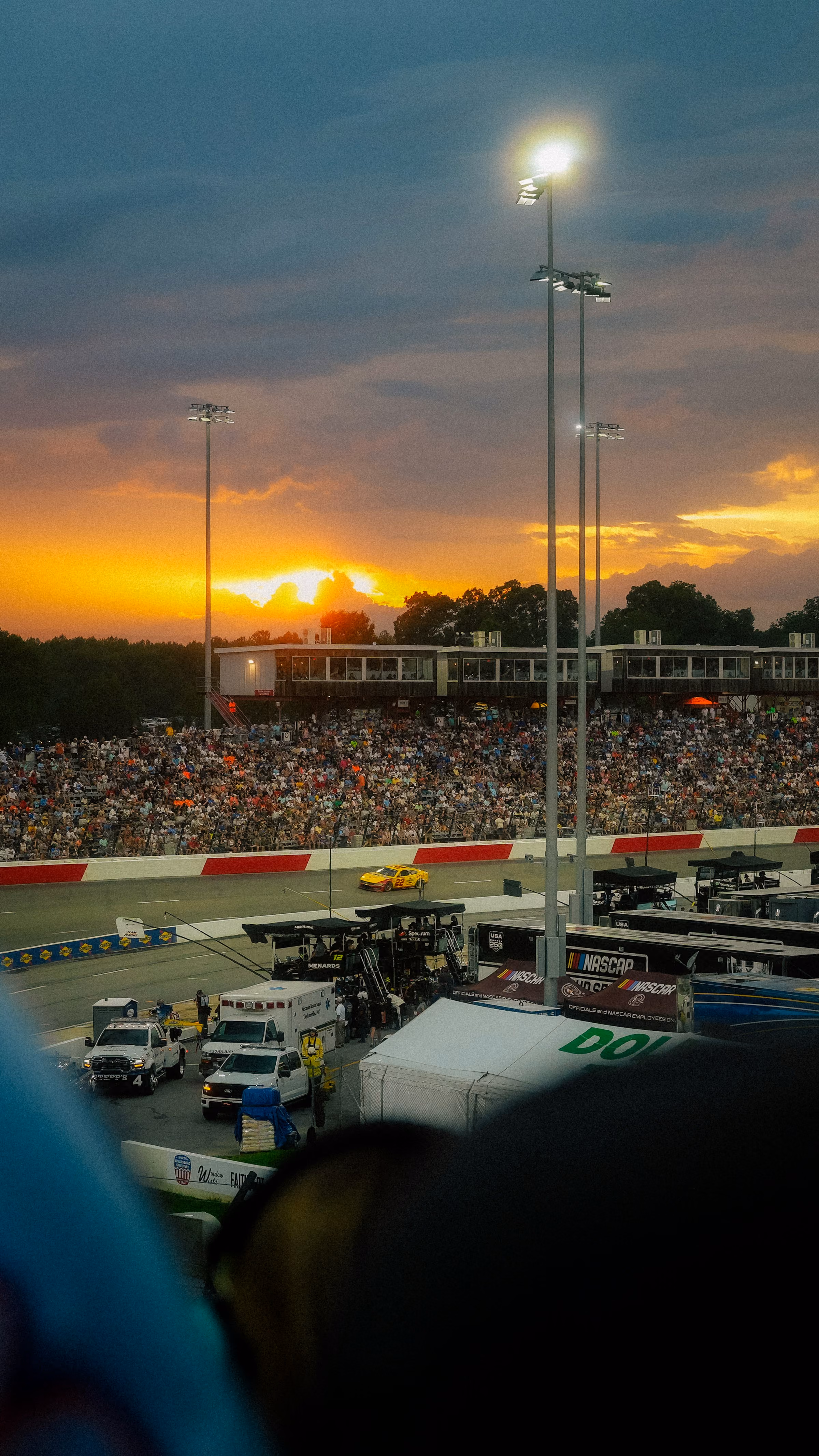 A grandstand crowd at a race circuit at sunset