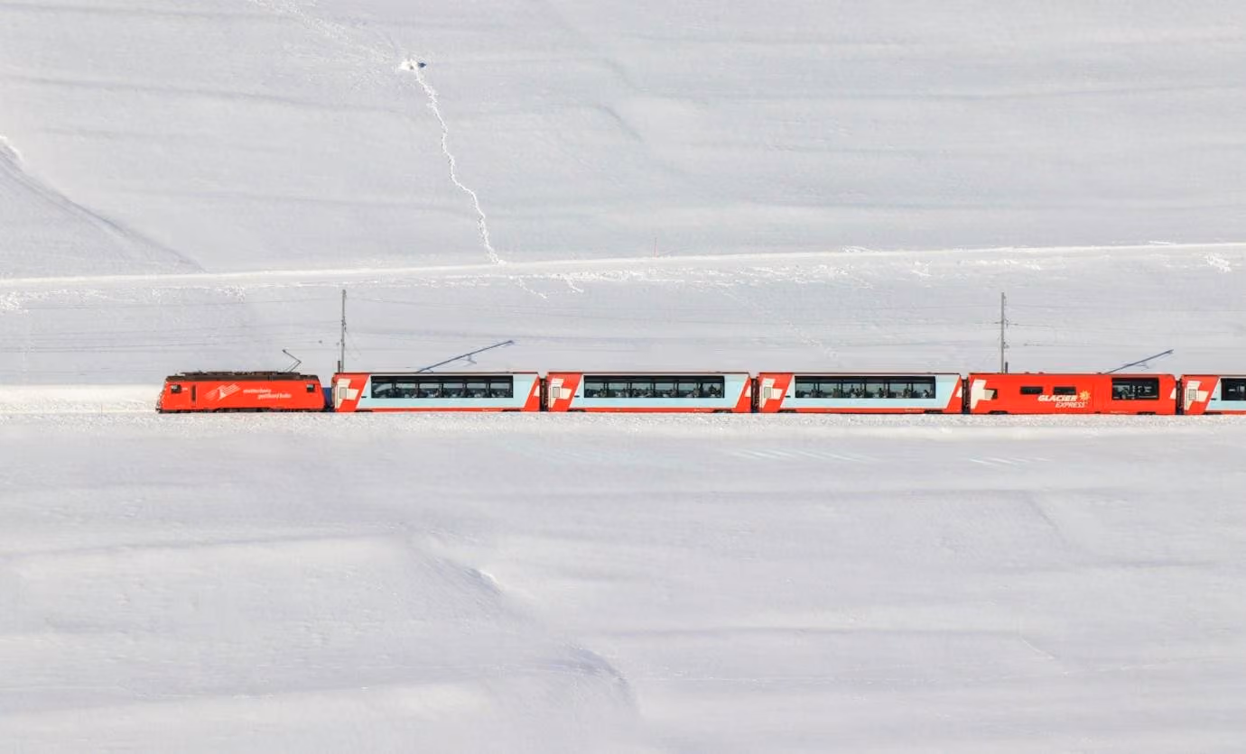 A red Glacier Express crossing a white snowfield