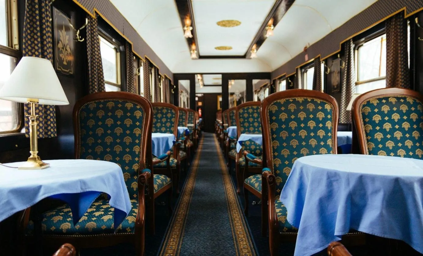 A vintage dining car with gold-patterned blue chairs