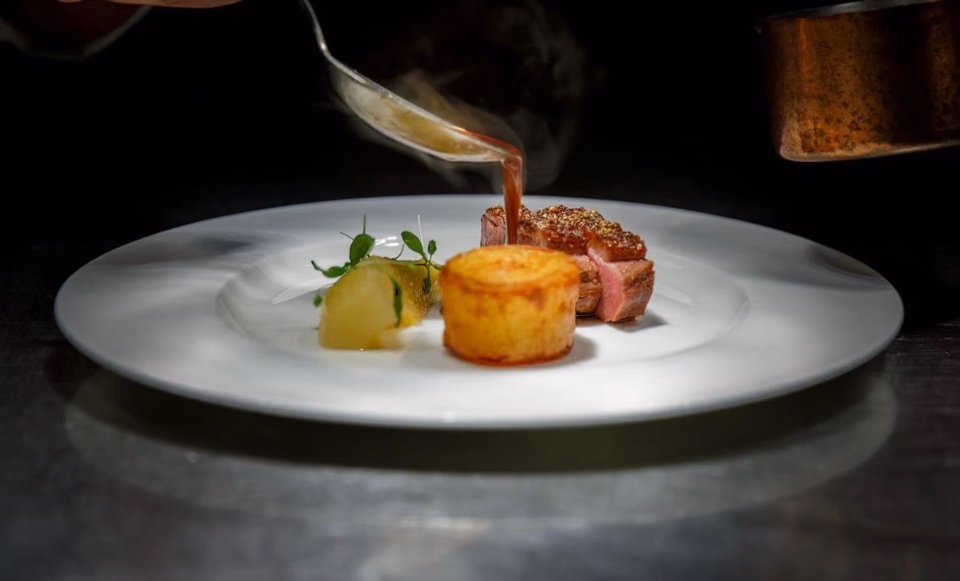A tasting menu course being sauced at the table