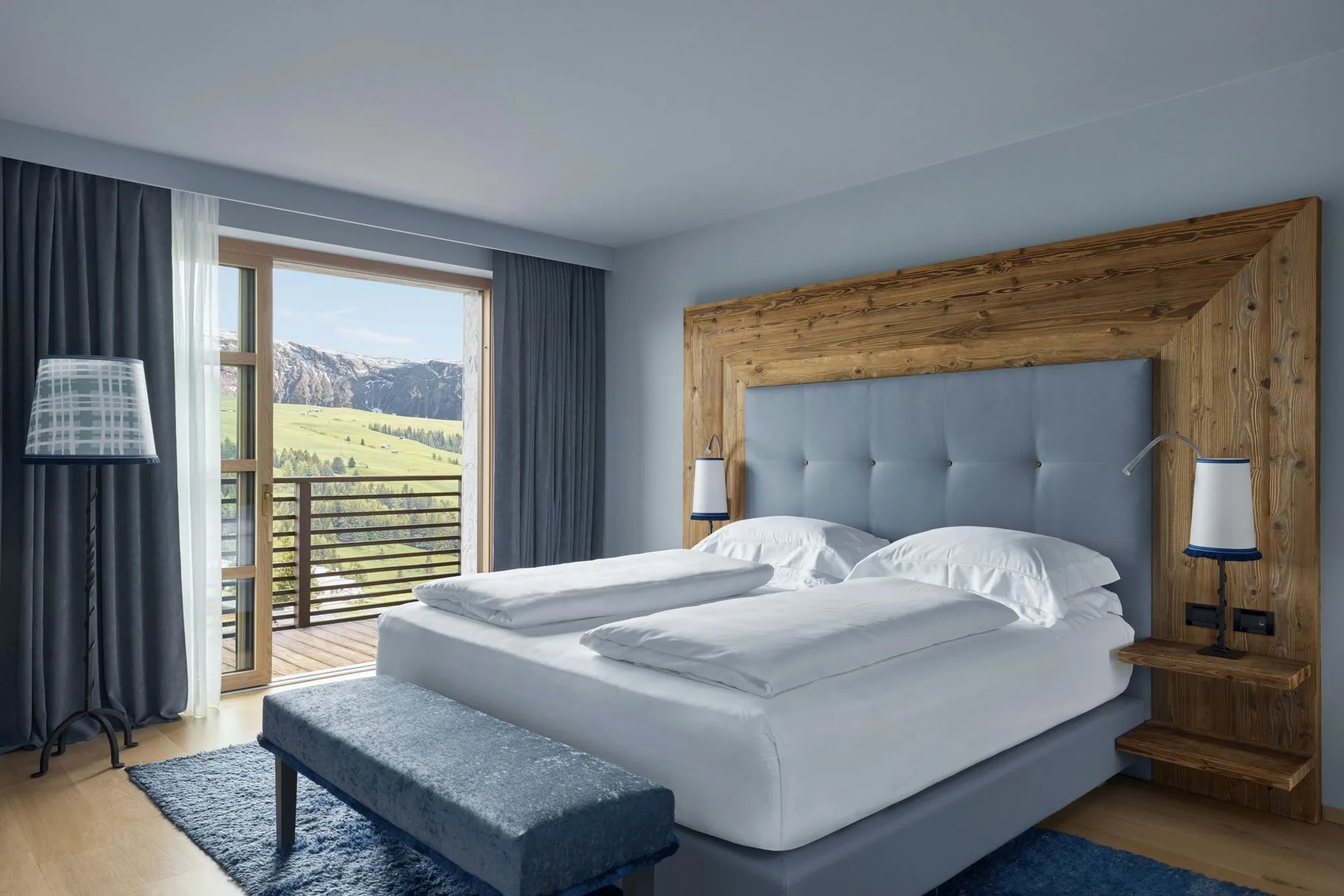 A Mountain Suite at COMO Alpina Dolomites, with a king bed and a balcony onto the mountains