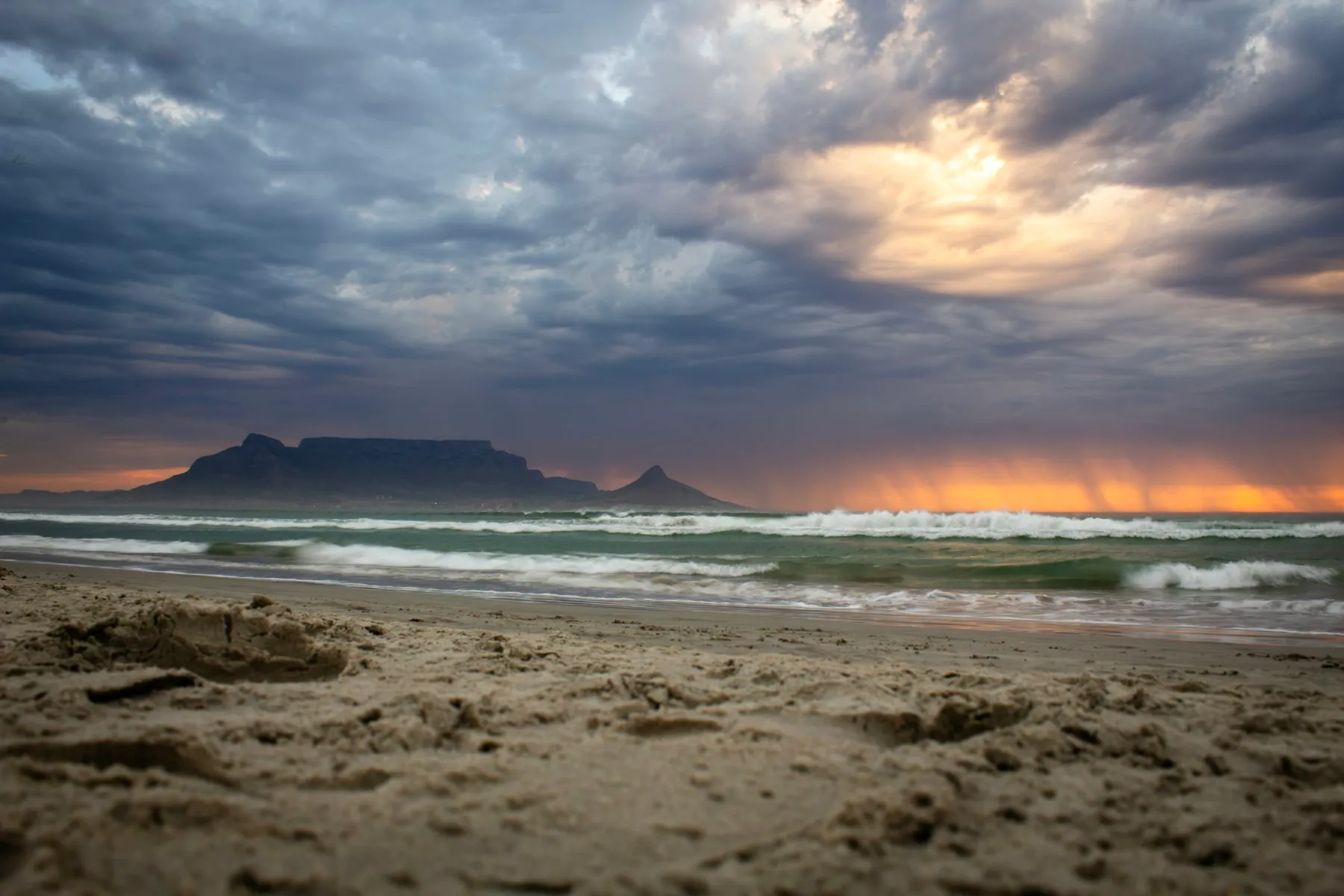 Table Mountain and Lion's Head under a stormy sunset sky, seen from the beach at Bloubergstrand, planning the best time to visit South Africa