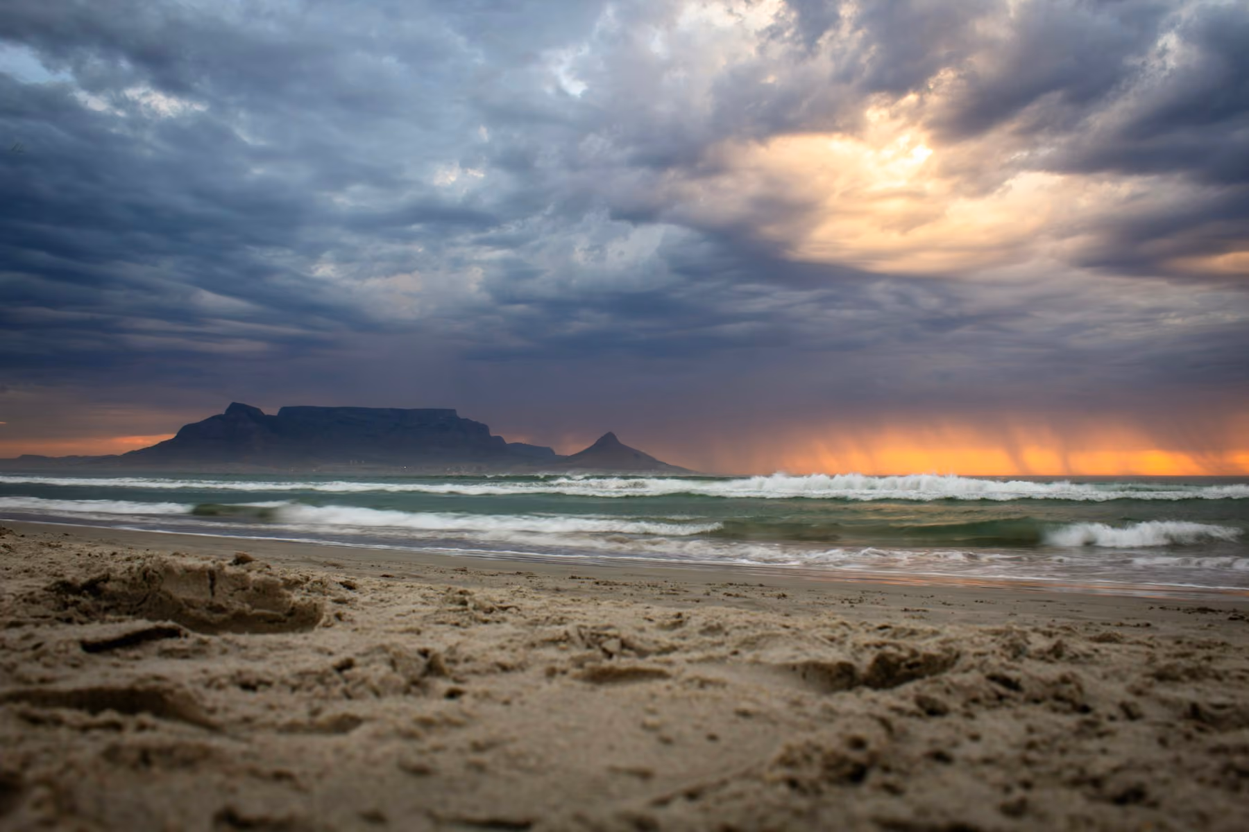 Table Mountain and Lion's Head under a stormy sunset sky, seen from the beach at Bloubergstrand, planning the best time to visit South Africa