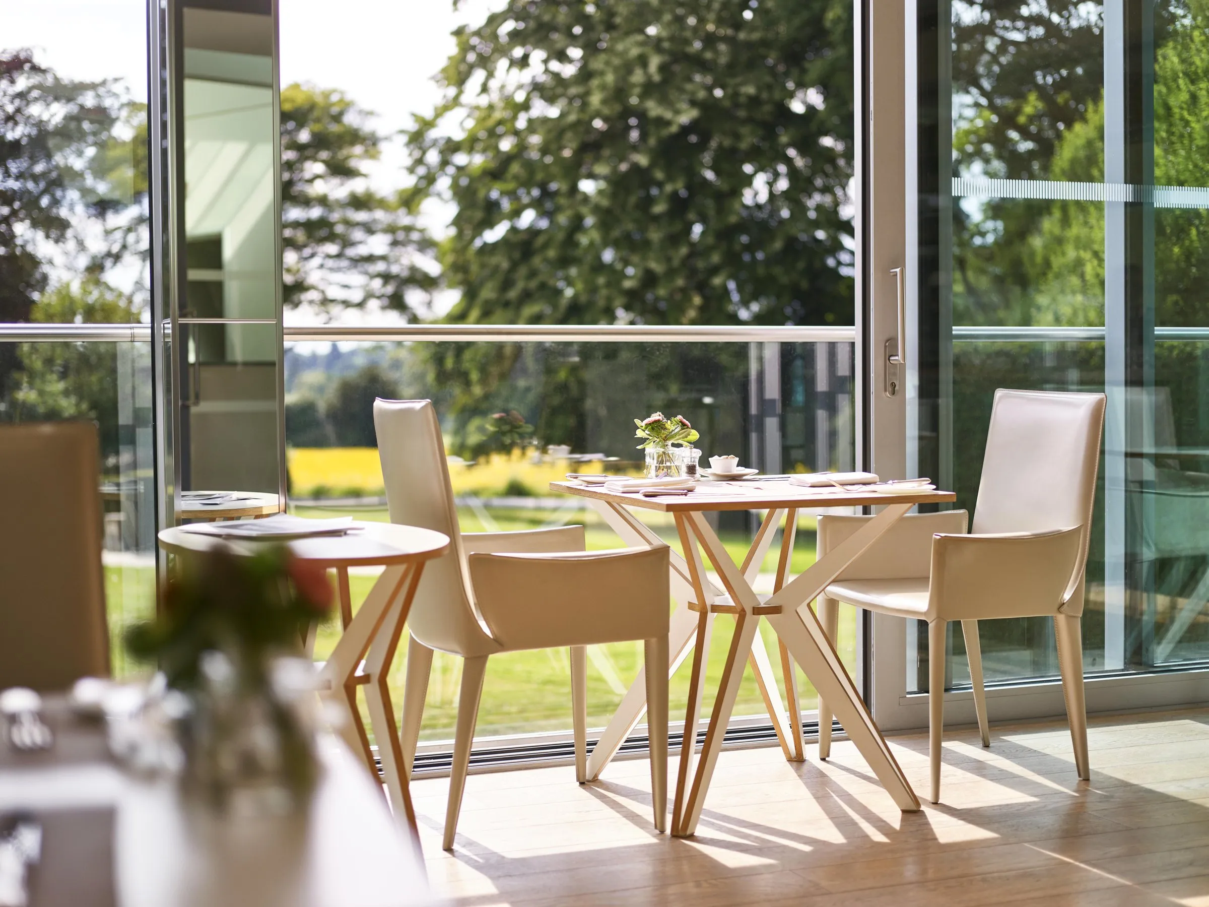 Tables by open glass doors in the Spa Café, looking on to the trees