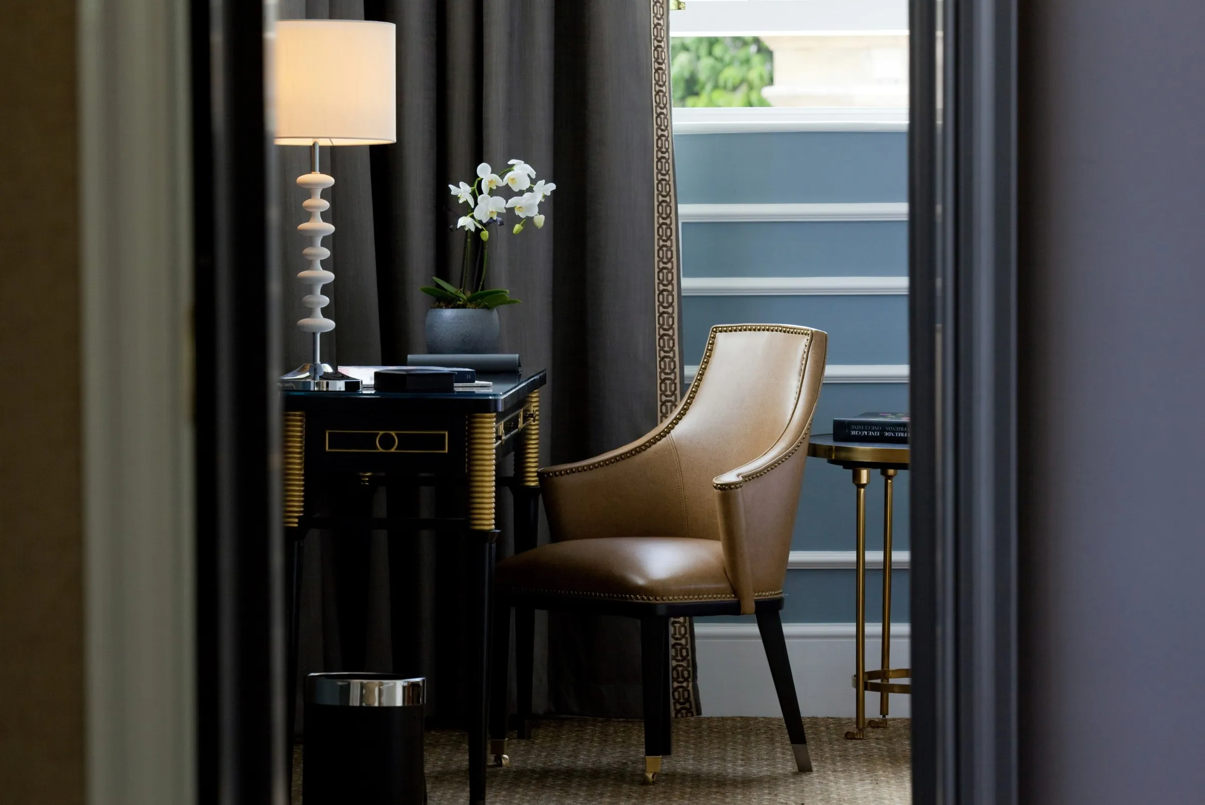 A deluxe room with an armchair, desk and tall windows