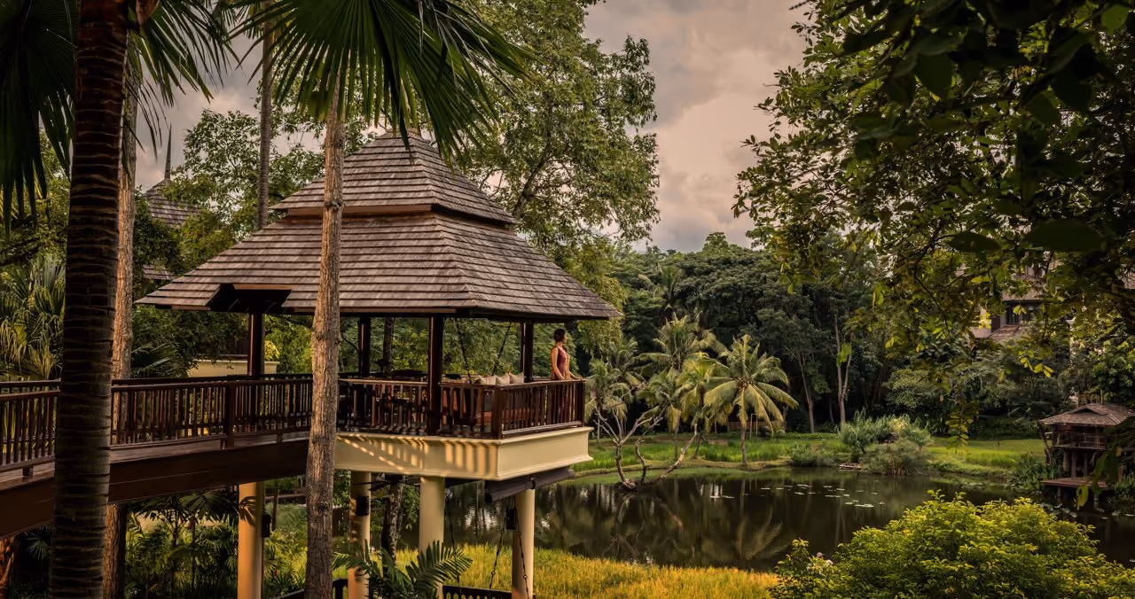A raised teak sala among palms above a pond at Four Seasons Resort Chiang Mai