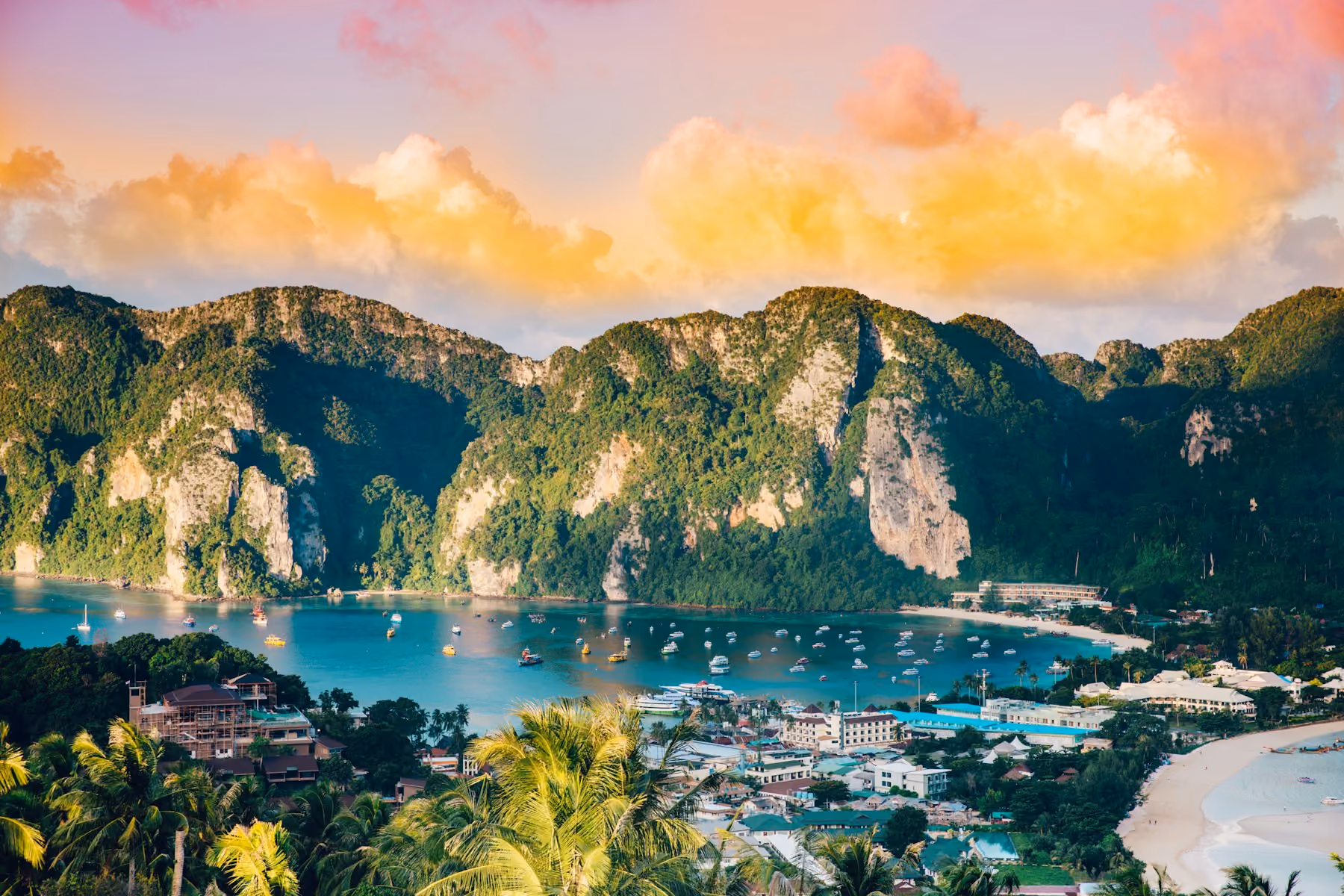 Boats in the bay at Phi Phi Don below green limestone hills